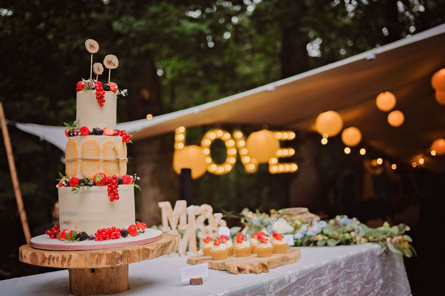 Desserttafel met houten taartstandaards en lichtjes, sfeervolle bruidsfotografie bij Mr van Eijck Oisterwijk, Brabant.