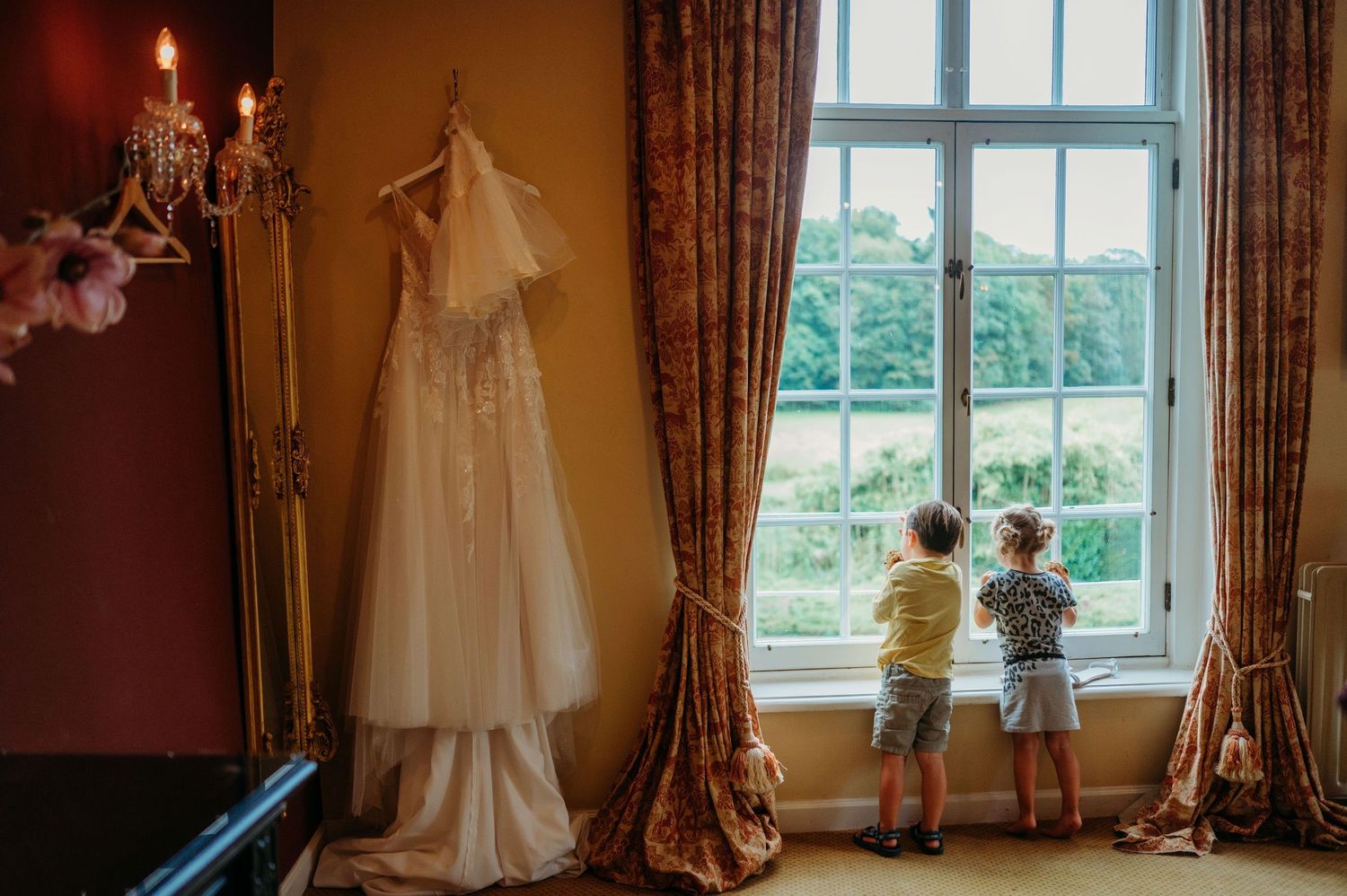 Kinderen kijken door raam in elegante kamer met gordijnen en natuurlijk licht, familieshoot Vught, Brabant op Kasteel Maurick