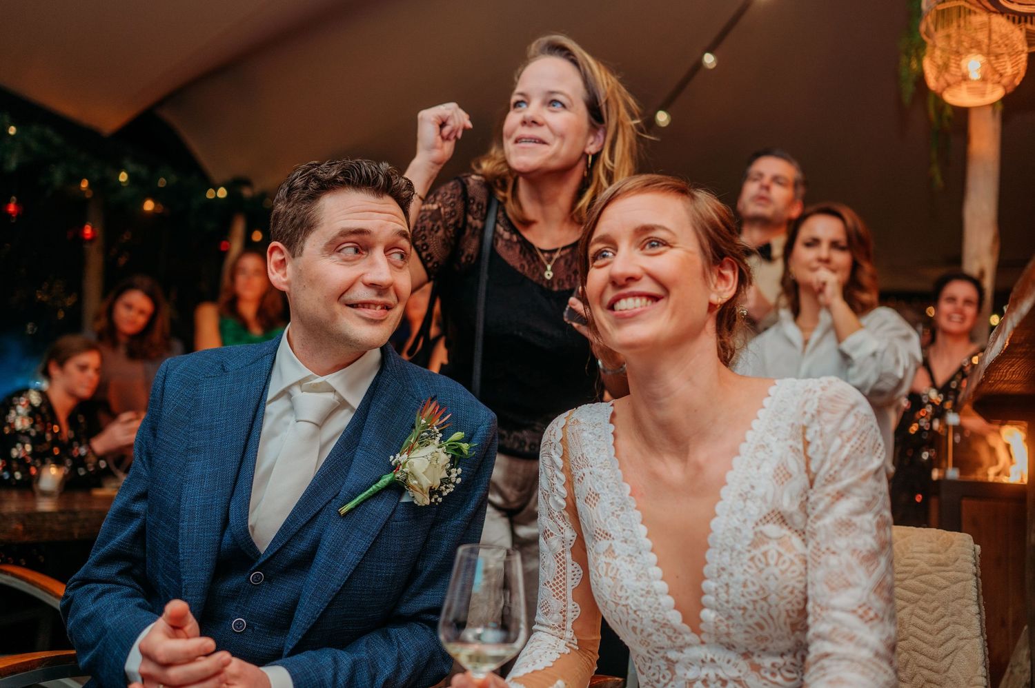 Bruiloftsgasten lachen en genieten tijdens feest binnen, spontane bruidsfotografie bij Boscafé Oisterwijk, regio Brabant.