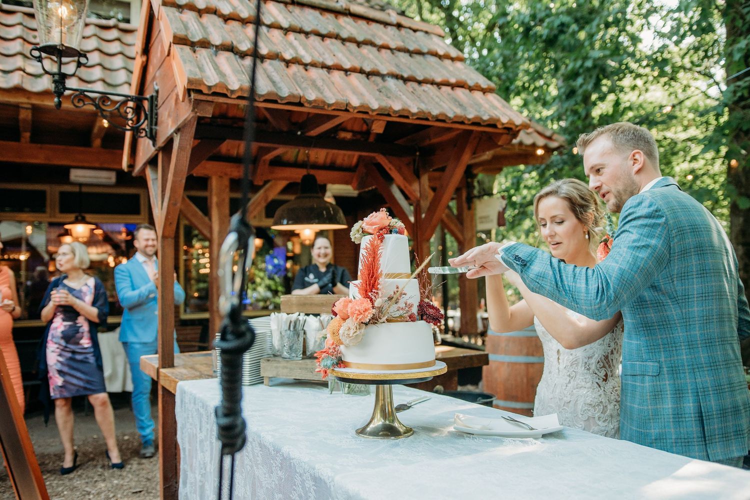 Buitenfeest onder houten overkapping met gasten, spontane bruidsfotografie bij Mr van Eijck Oisterwijk, Brabant.