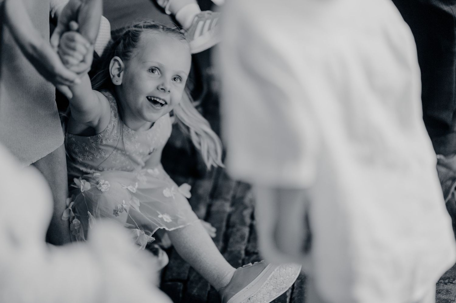 Joyful young flower girl laughing during wedding celebration in black and white photo.
