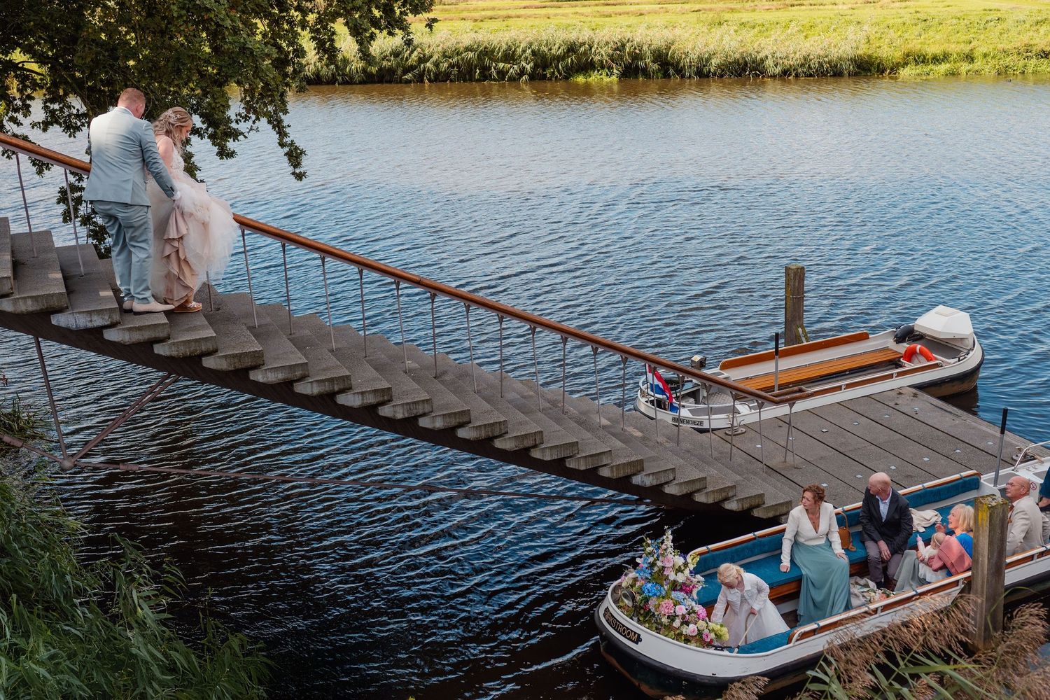 Gasten genieten van boottocht op een rustig meer tijdens bruiloft, trouwfotografie Brabant.