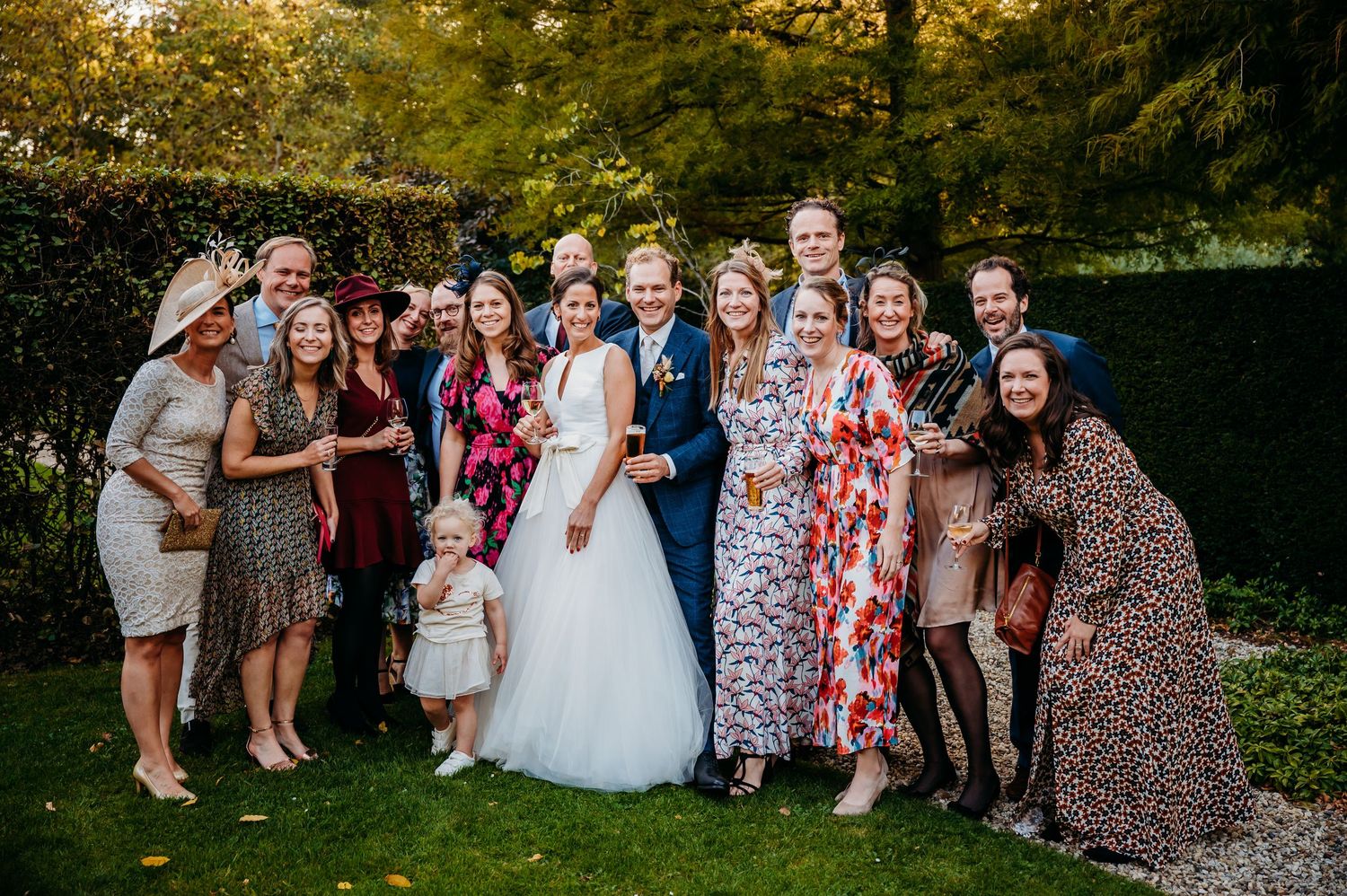 Groep bruiloftsgasten poseert buiten in kleurrijke kleding, bruidsfotografie Kasteel Maurick Vught, Brabant.