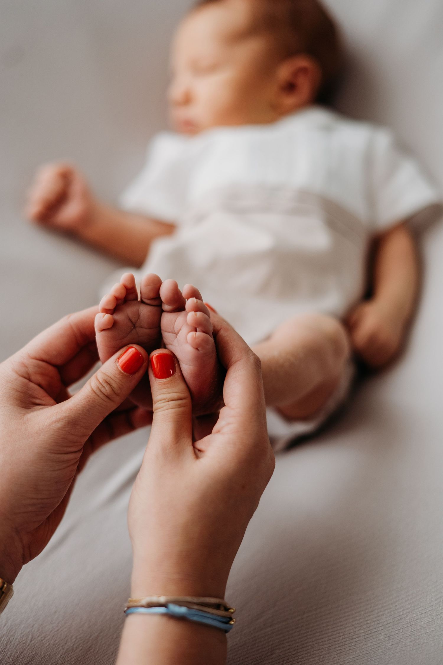 Zachte handen masseren kleine babyvoetjes tijdens teder moment, newbornfotografie Brabant
