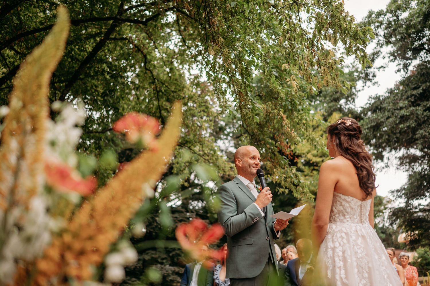 Buiten ceremonie in een groene tuin met bloemen tijdens een bruiloft in Brabant gefotografeerd door bruidsfotograaf Den Bosch
