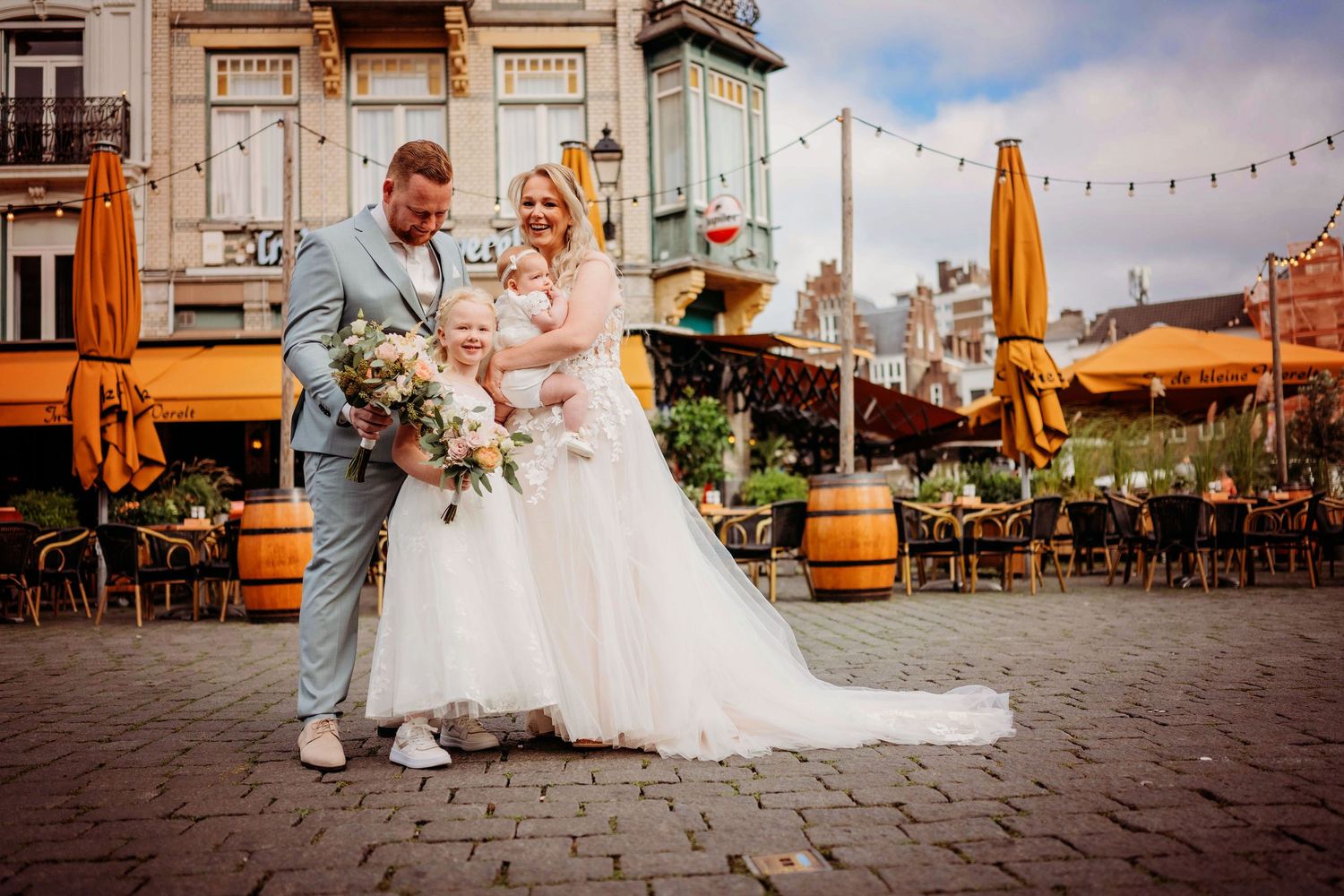 Bruiloftsfeest op terras met oranje parasols en sfeerverlichting, spontane bruidsfotografie in Den Bosch en omgeving Brabant.