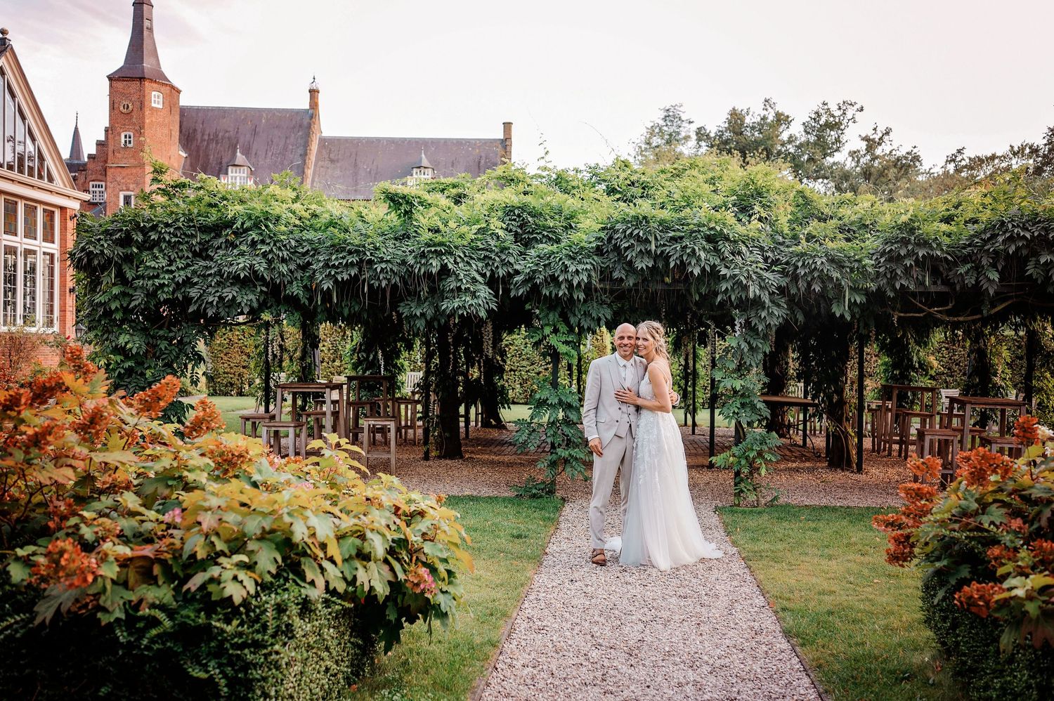 Ceremonie op tuinpad met bomen en bloemen, bruidsfotografie Vught, Brabant.