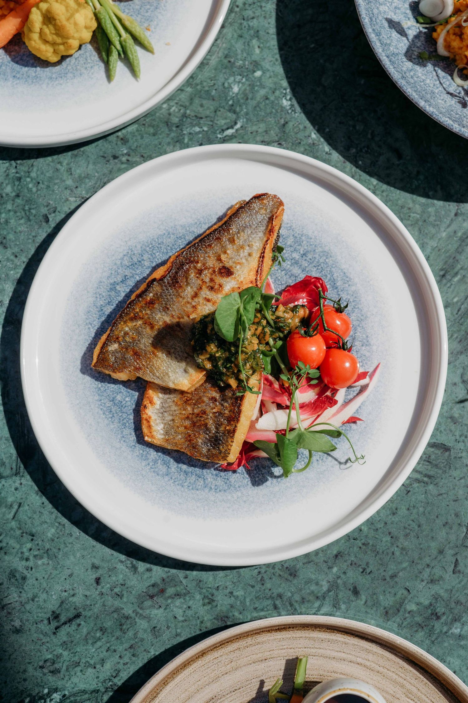 Gebakken visfilets met kleurrijke garnituren op wit porselein, foodfotografie Brabant