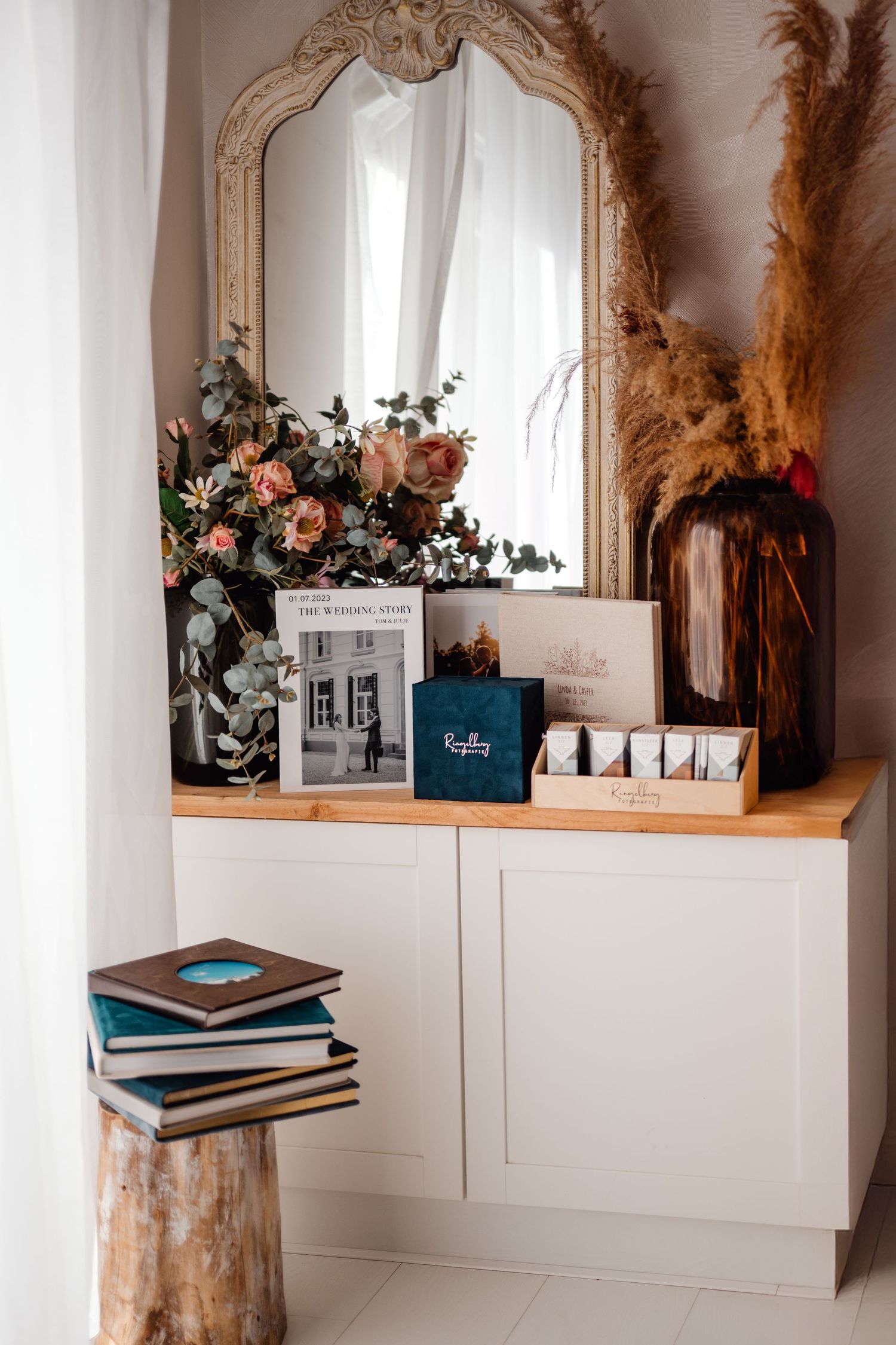 Modern shelf styling with wedding albums, floral arrangements and decorative elements.