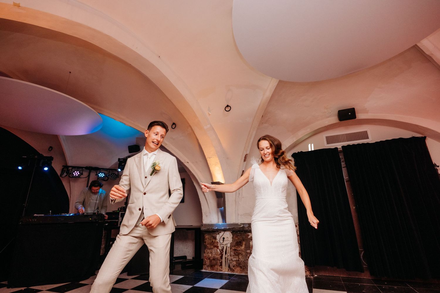 Bruiloftsgasten dansen tijdens trouwfeest onder bogen met sfeervol licht, spontane bruidsfotografie in Brabant regio Den Bosch.