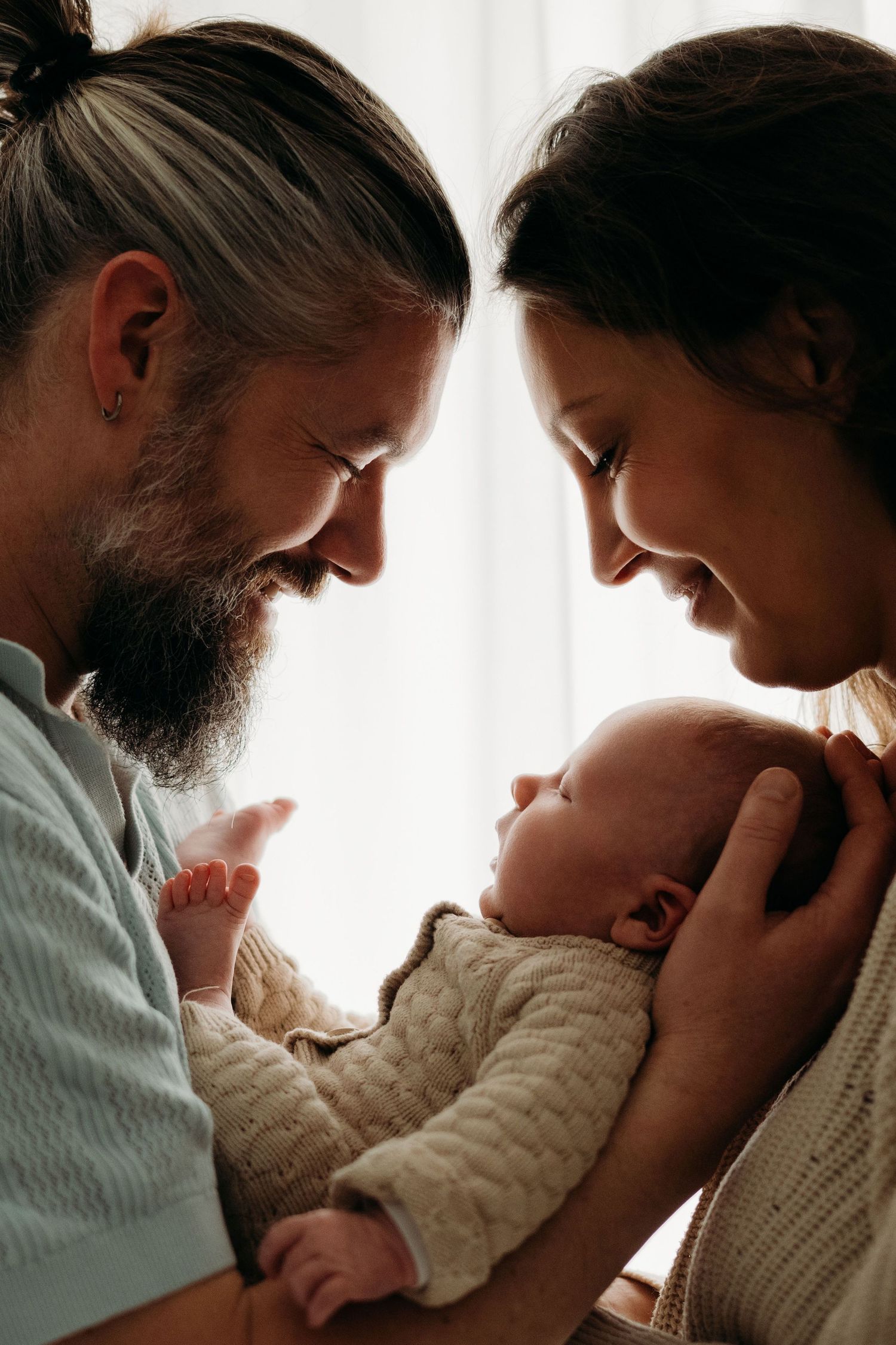 Ouder en baby moment bij raamlicht tijdens newbornshoot in Vught, emotionele en pure fotografie