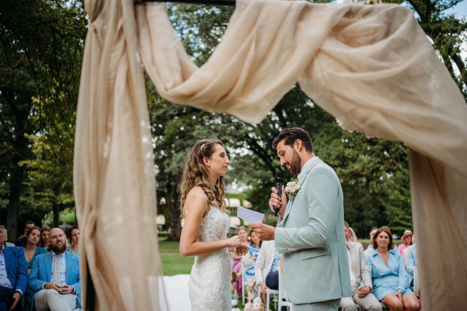 Outdoor ceremonie met vloeiende doeken en natuurlijke groene decoratie, bruidsfotografie Brabant