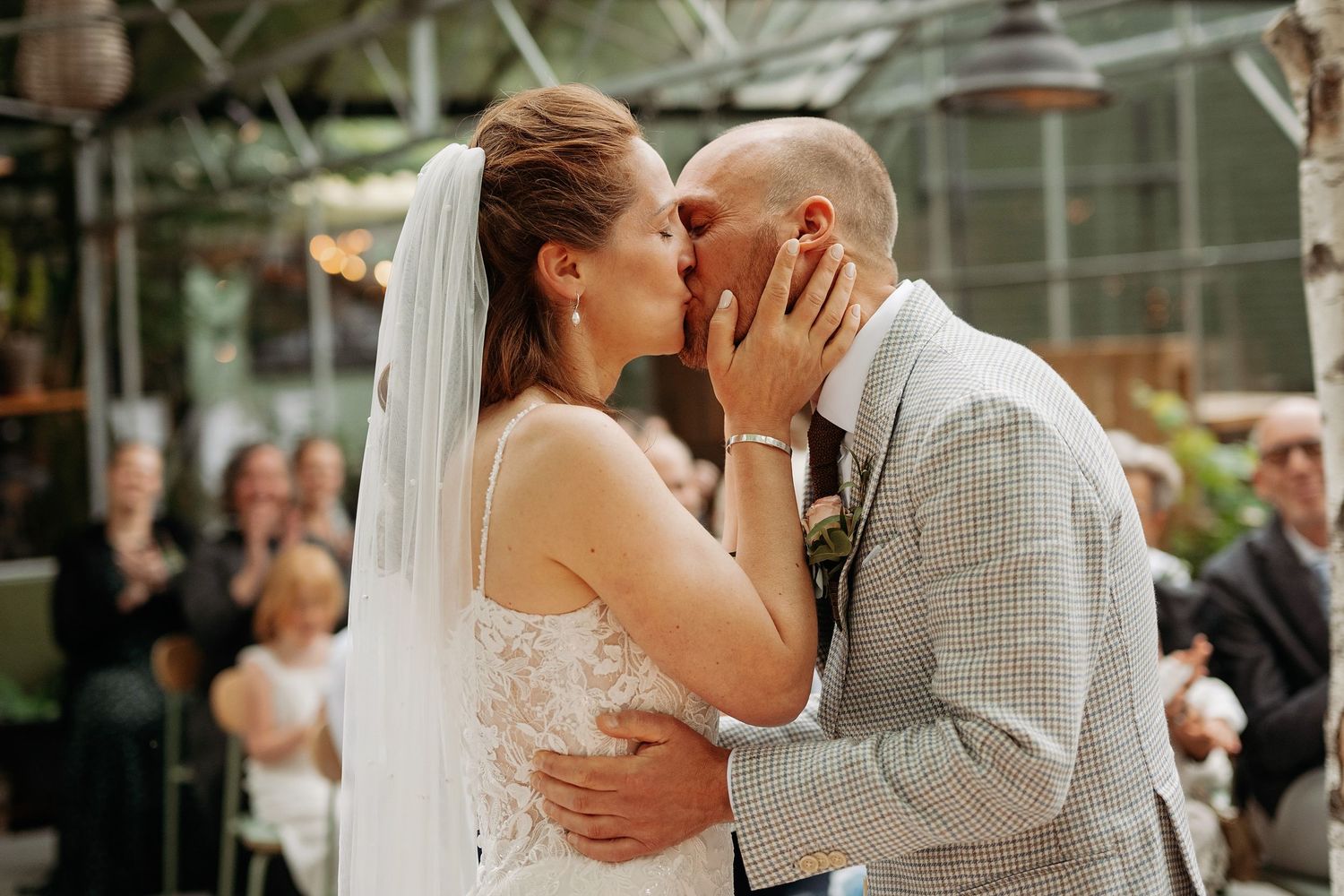 Bride and groom share their first kiss as husband and wife at indoor greenhouse wedding.