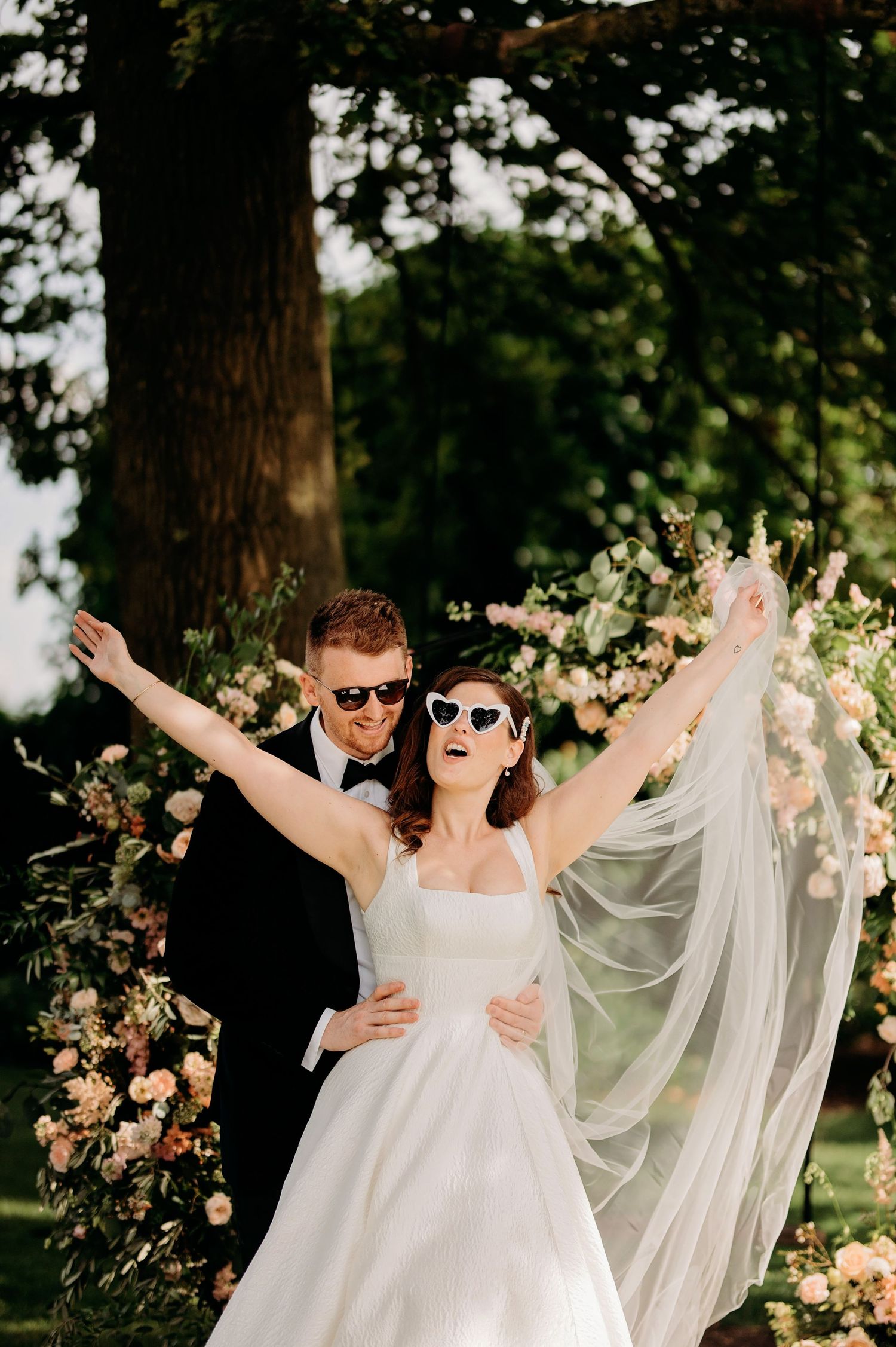 Bruiloftsfeest met vloeiende sluier en bloemdecoraties in buitentuin, bruidsfotografie Brabant