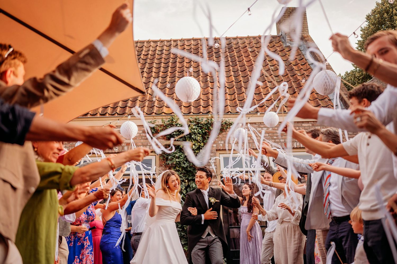 Trouwreceptie met gasten die witte ballonnen in de lucht gooien.