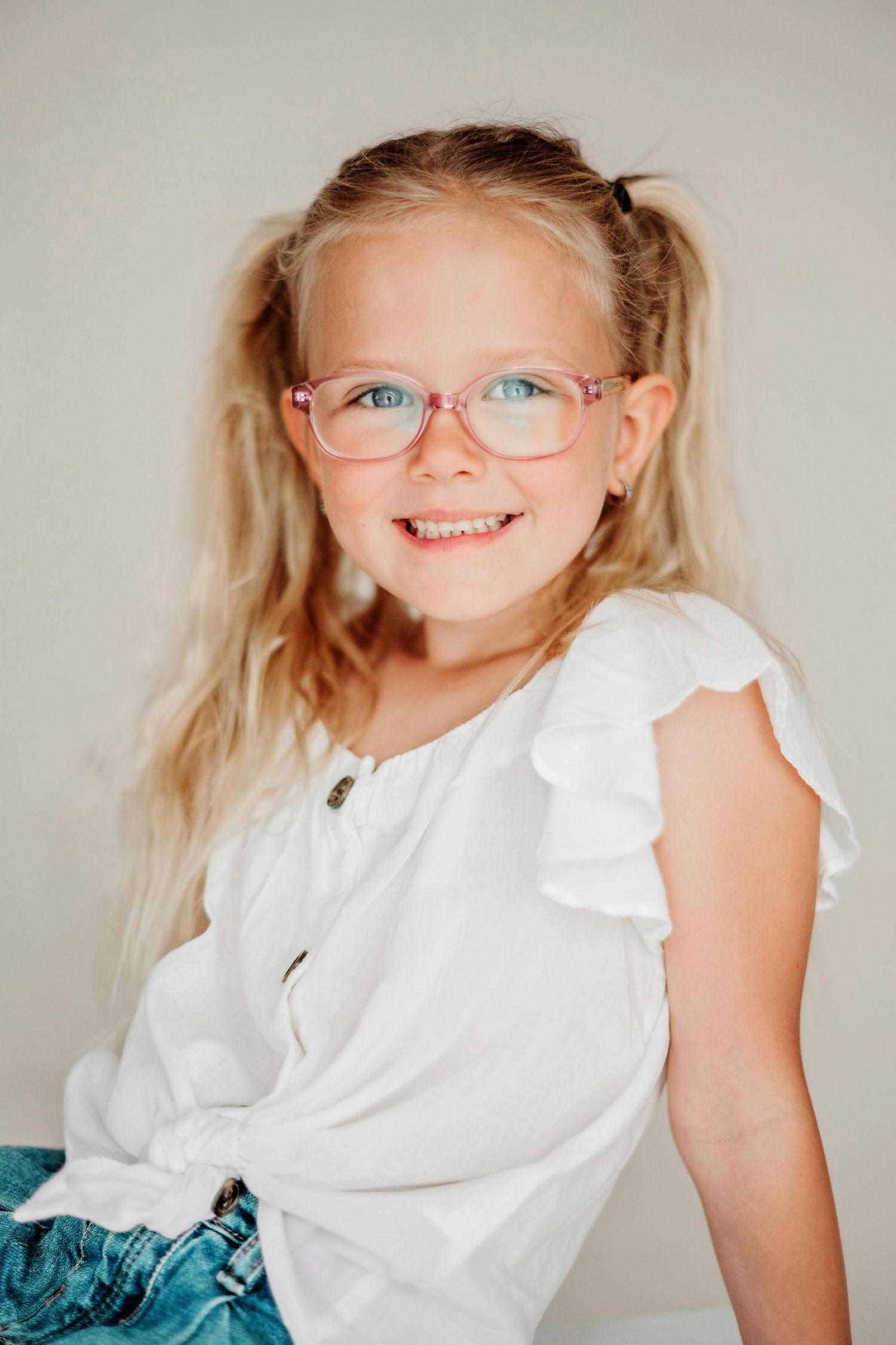 Kinderportret met bril en witte kleding in studio in Vught, spontane en vrolijke fotoshoot