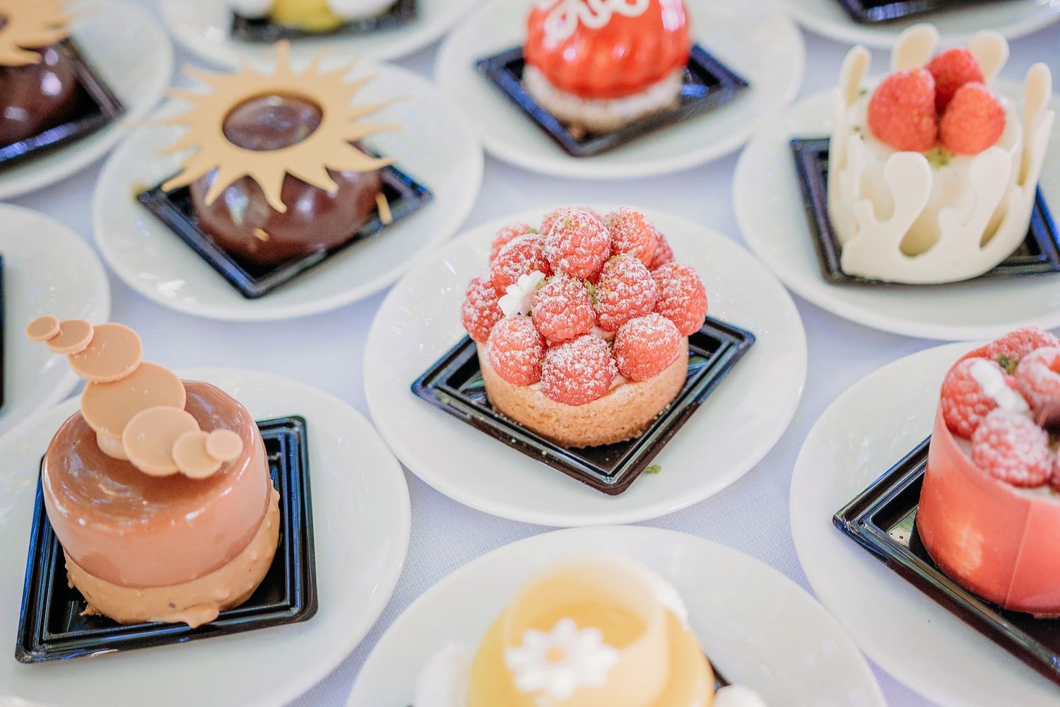 Dessertbuffet met roze en chocolade mini cakes op witte borden, bruidsfotografie Kasteel Maurick Vught, Brabant.