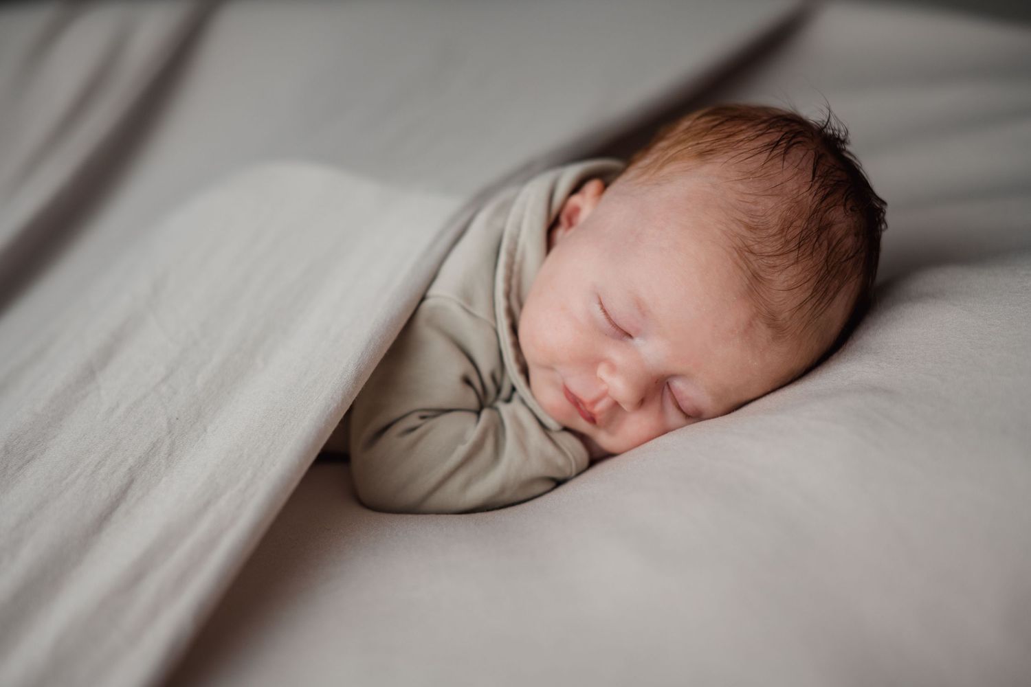 Peaceful newborn photography with soft gray tones and gentle lighting.