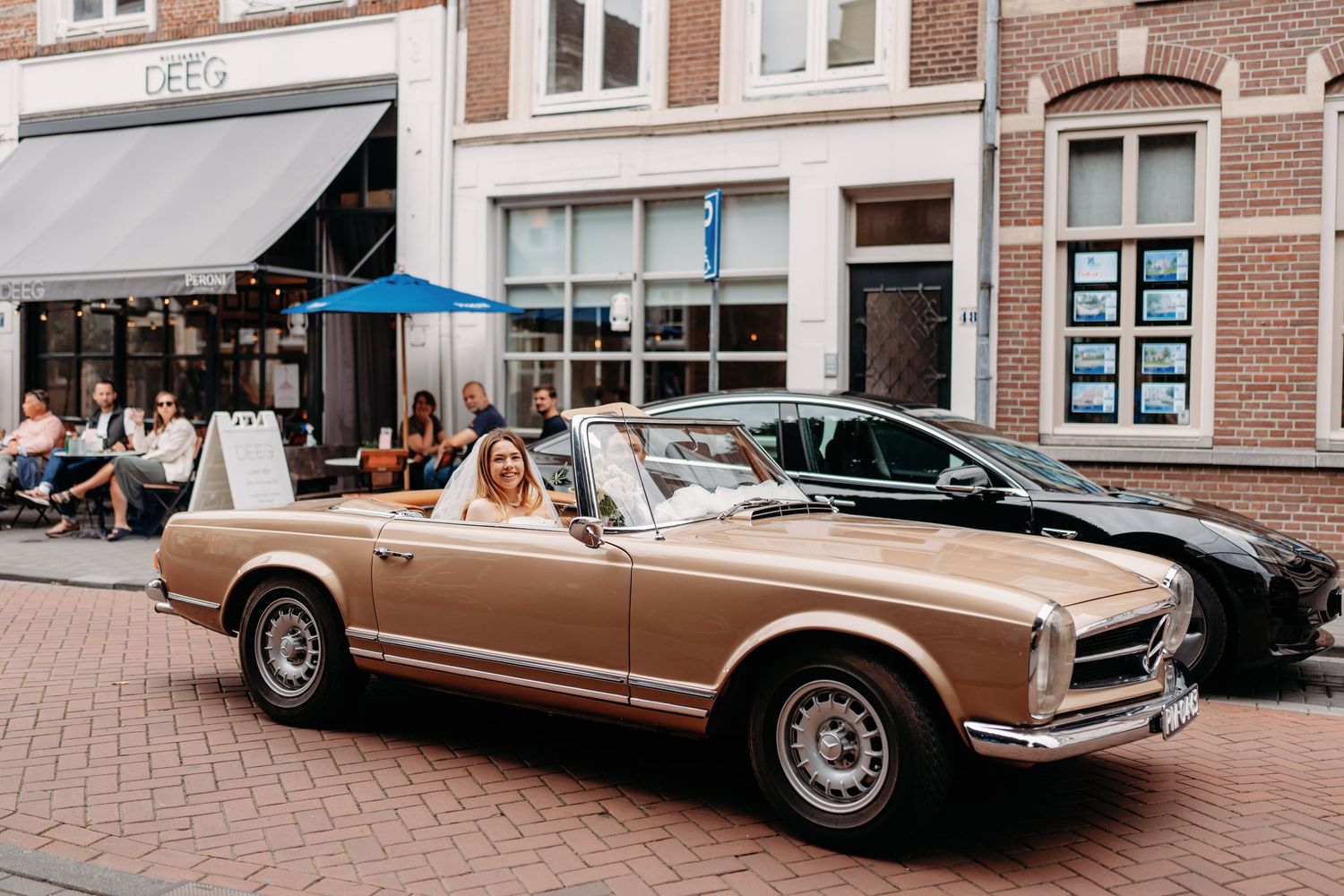 Klassieke Lincoln Continental geparkeerd op bakstenen straat voor historisch gebouw, bruidsfotografie Noordbrabants Museum Den Bosch, Braban