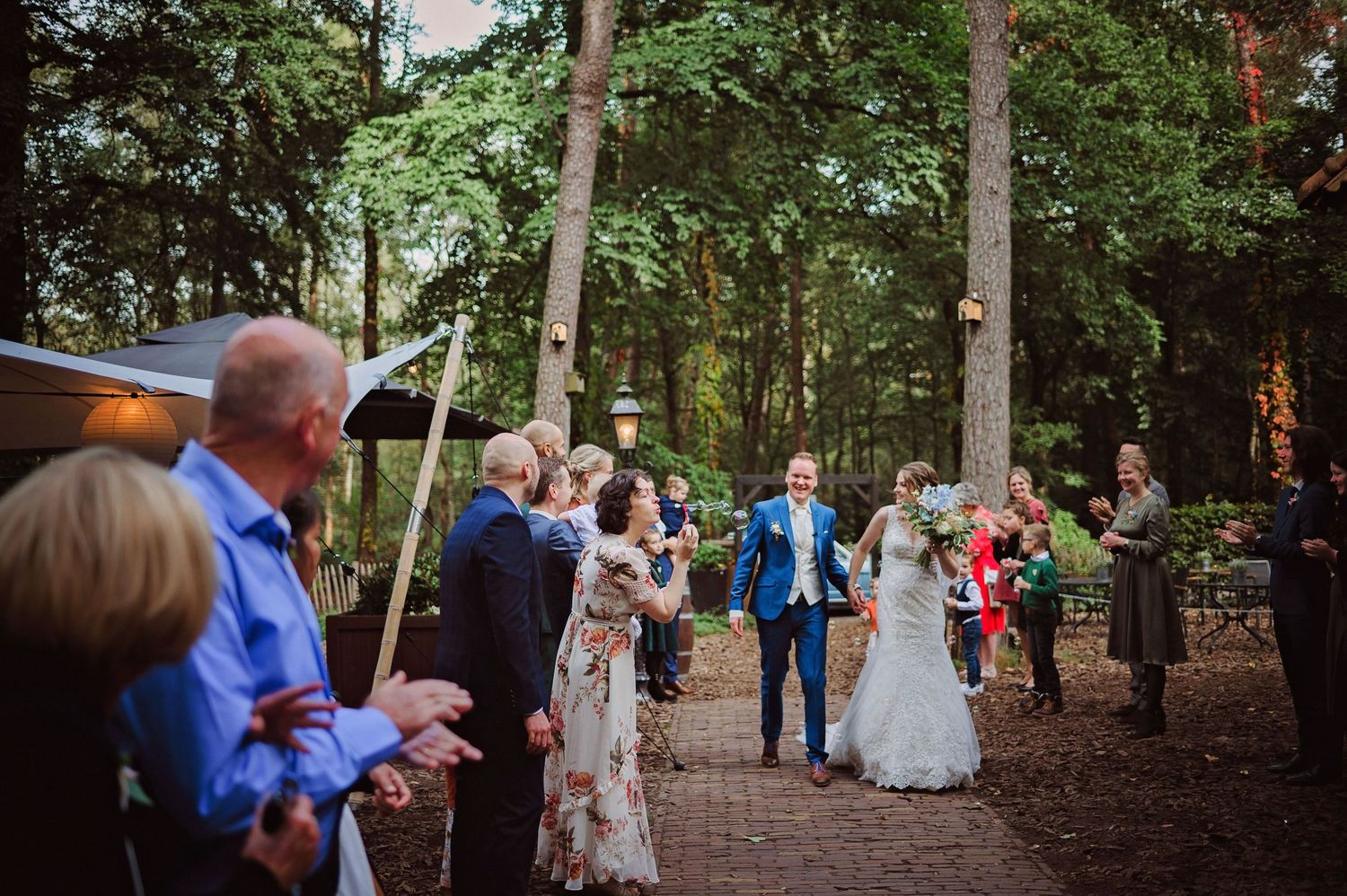 Bruiloftsgasten langs bospad tijdens intieme ceremonie, spontane bruidsfotografie bij Mr van Eijck Oisterwijk, Brabant.