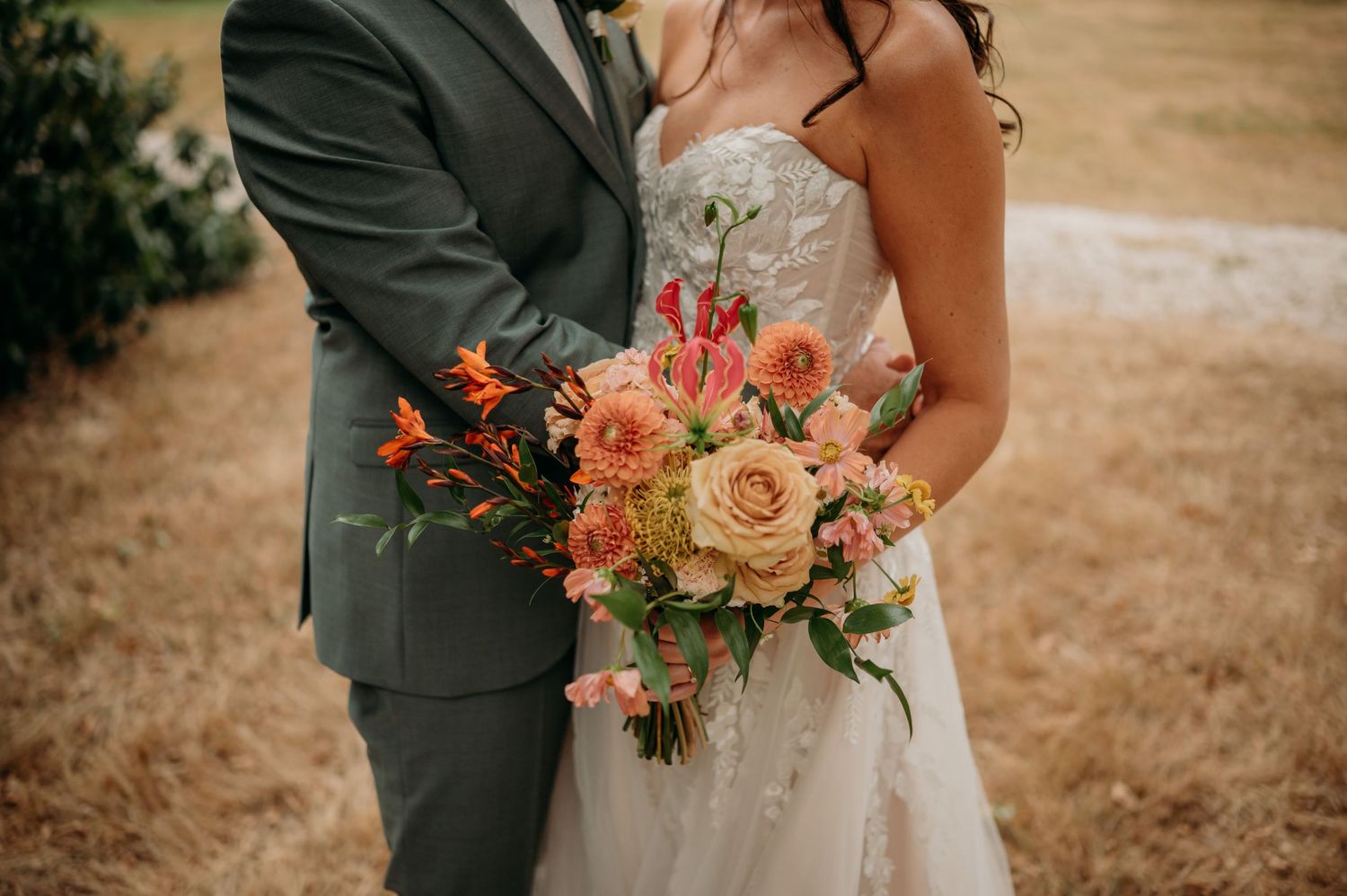 Bruidspaar met bloemenboeket in warme tinten tijdens een fotoshoot op hun trouwdag op Huize Bergen in Vught