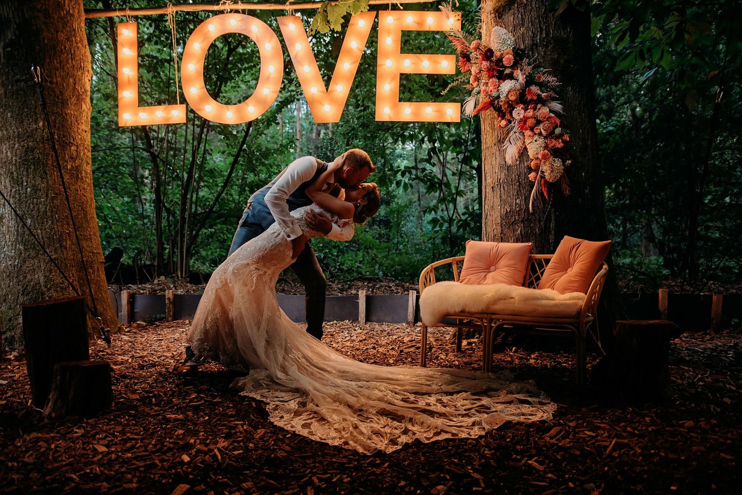 Bruidspaar samen tijdens romantisch avondmoment met verlichte letters LOVE, bruidsfotografie Brabant