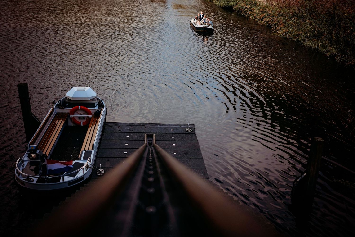 Twee bootjes op rivier bij schemer onder houten steiger, sfeervolle locatie en bruidsfotografie in Den Bosch en omgeving Brabant.