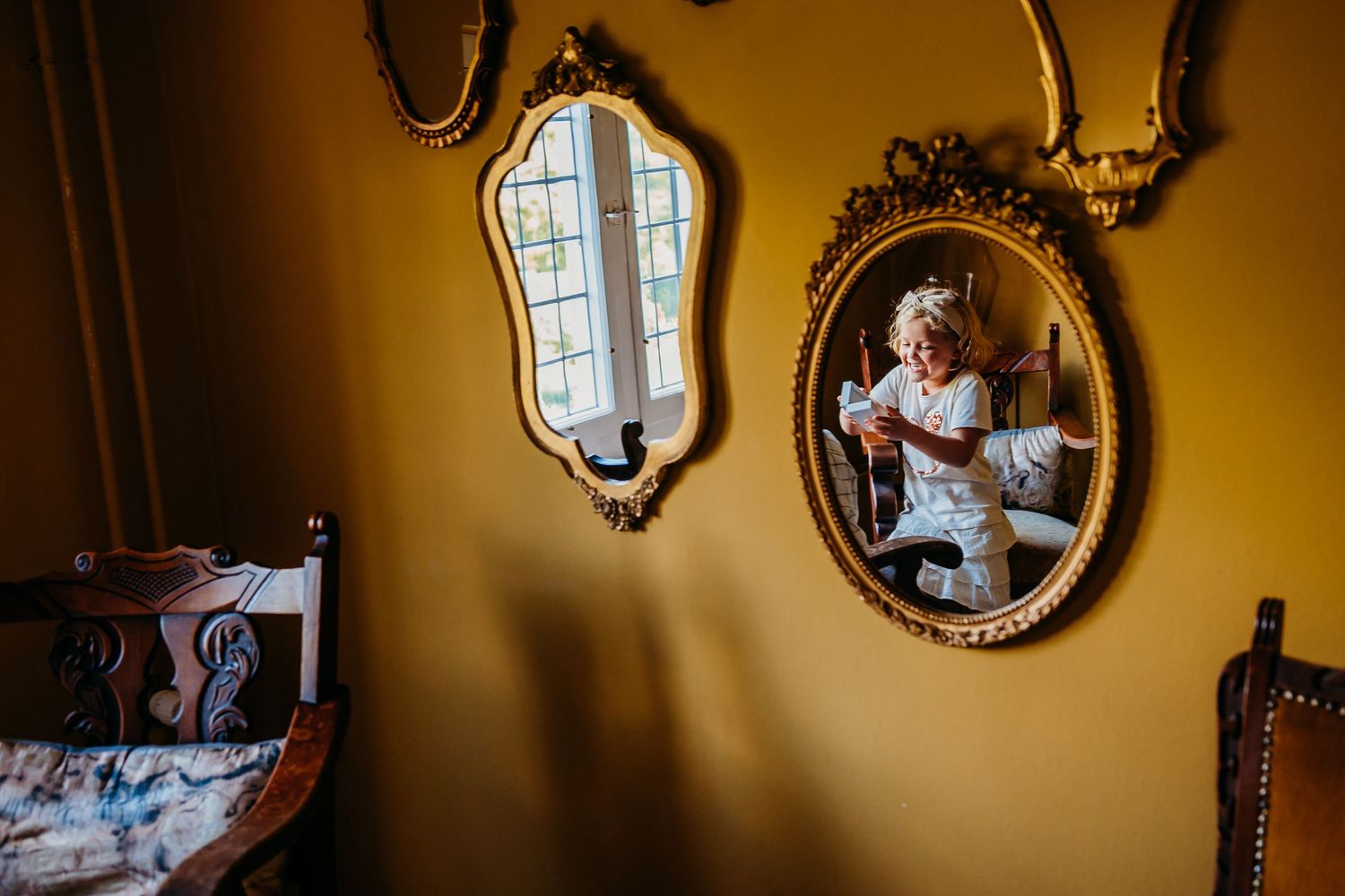Gouden spiegel reflecteert warm licht in elegante kamer, bruidsfotografie Kasteel Maurick Vught, Brabant.