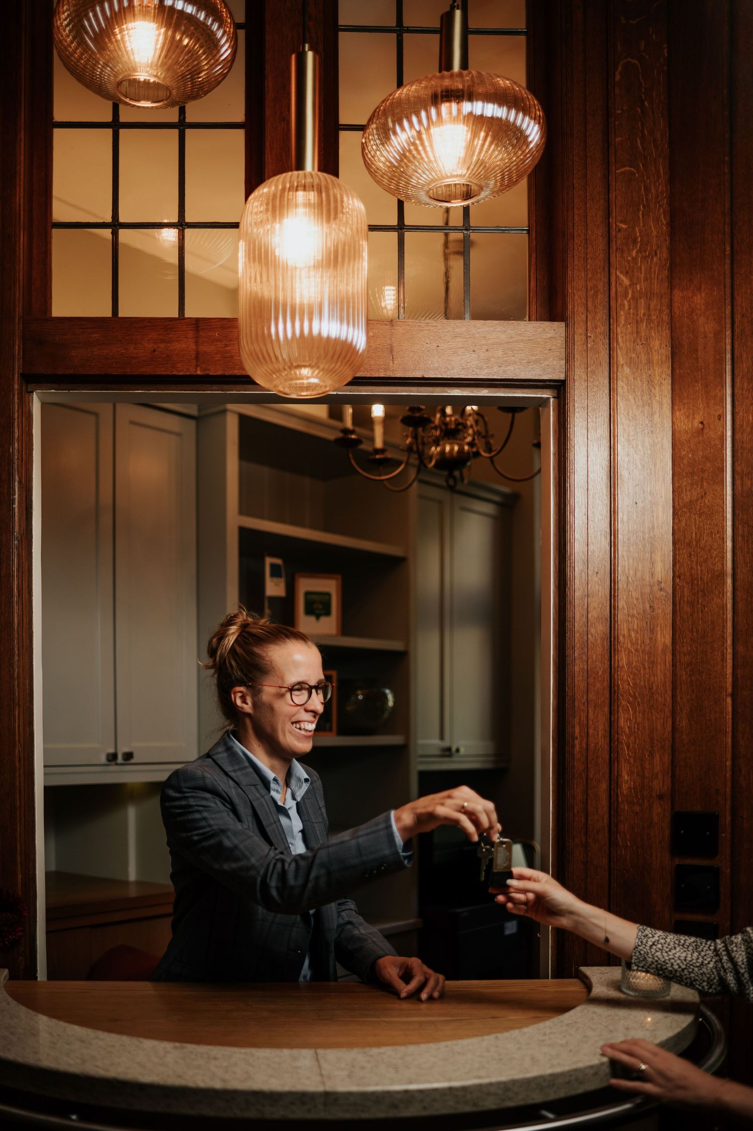 Moody bar met hanglampen en hout, handen op betonnen bar, sfeervolle hospitality fotografie Vught, Brabant.