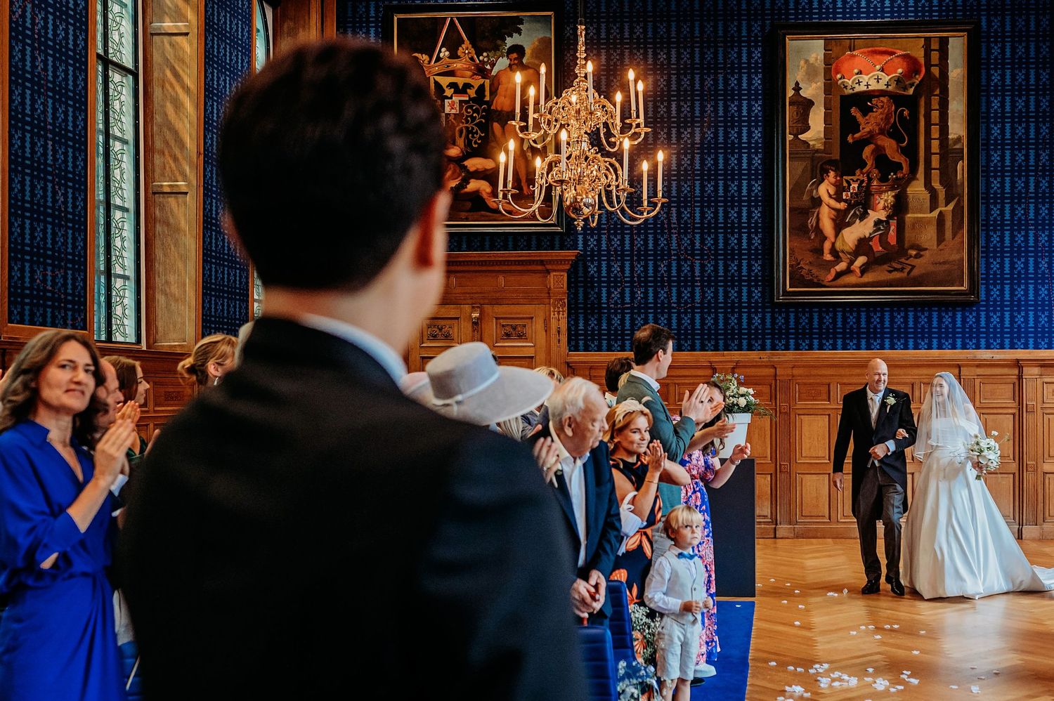 Bruiloft in een elegante blauwe en gouden balzaal met kroonluchters, trouwfotografie Brabant.