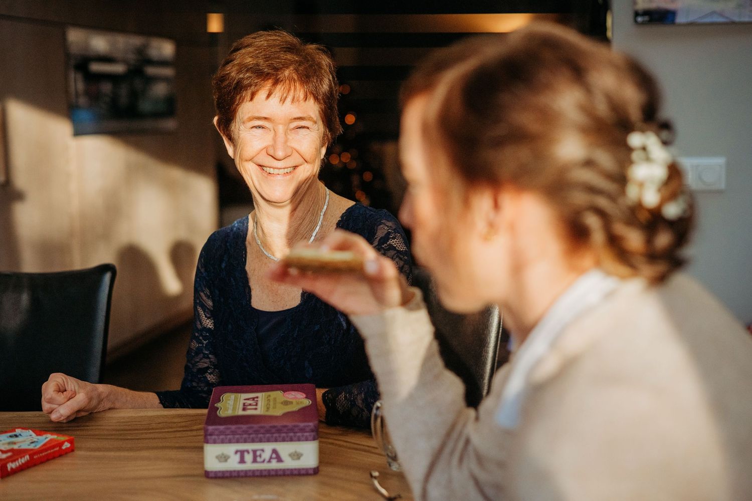 Twee gasten in gesprek bij tafel met thee, sfeervolle bruidsfotografie bij Boscafé Oisterwijk, Brabant.