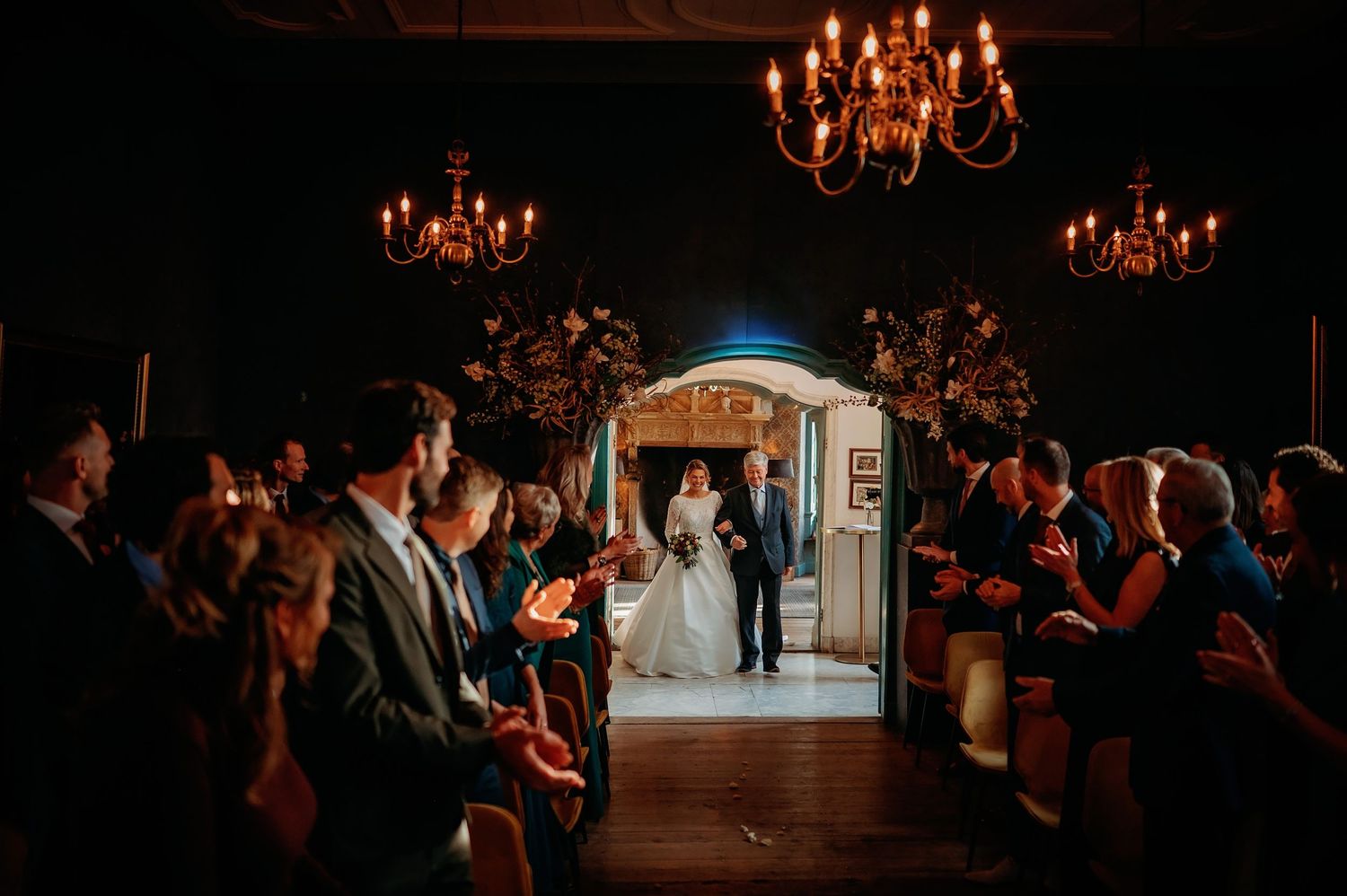 Elegante receptieruimte met warme kroonluchterverlichting en gasten aan tafels, trouwfotografie Brabant.