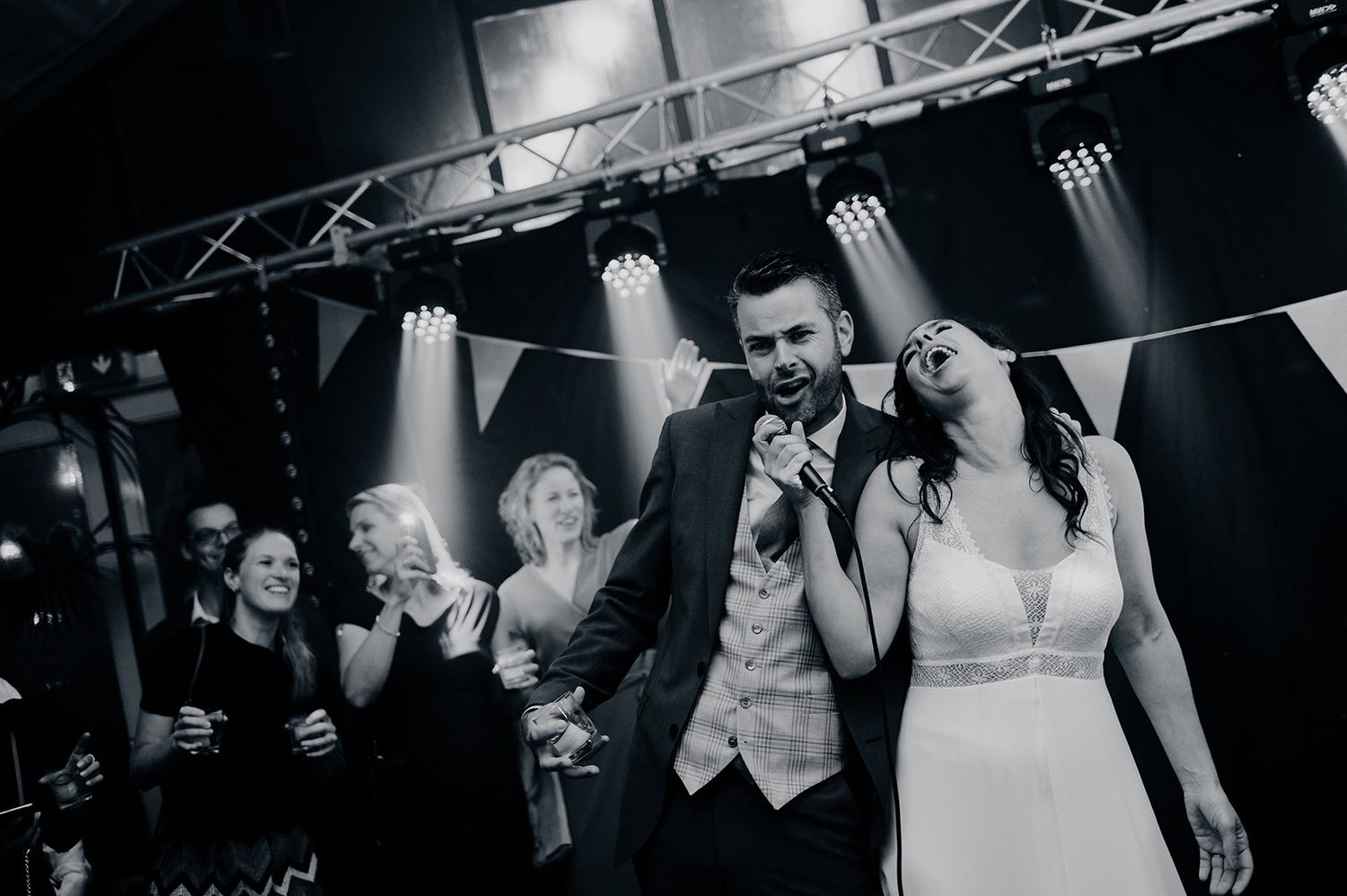 Vierend moment onder feestverlichting bij trouwfeest, bruidsfotografie Brabant