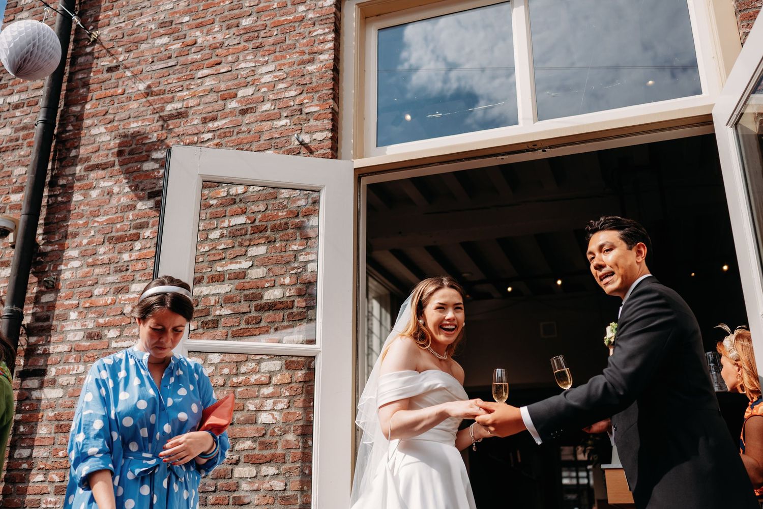 Buitengelegen viering met confetti en gasten bij bakstenen gebouw, bruidsfotografie Noordbrabants Museum Den Bosch, Brabant.