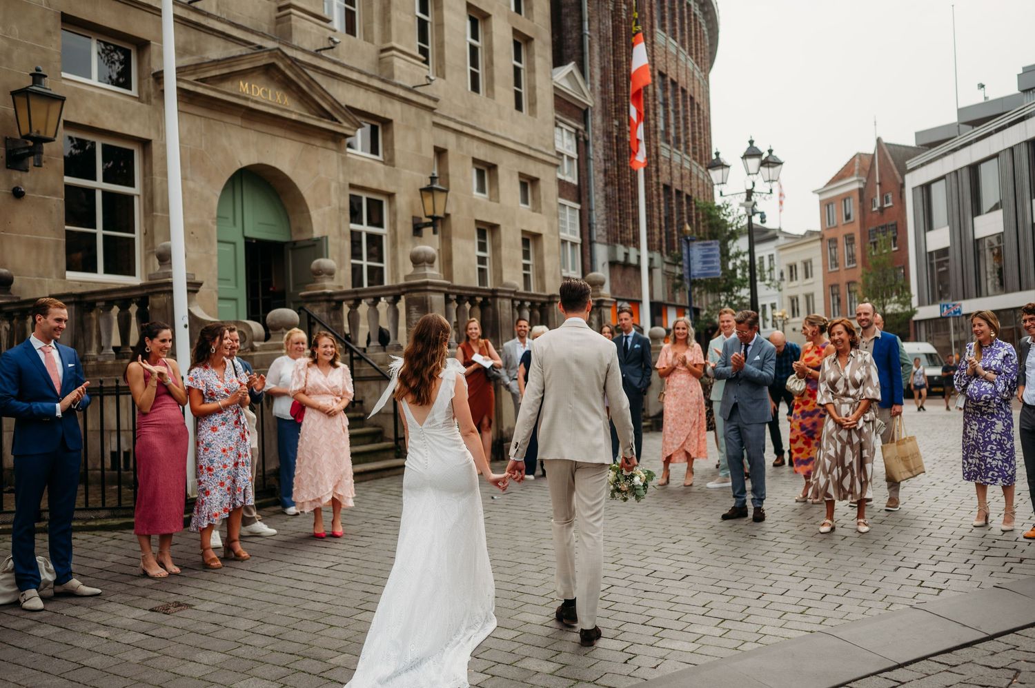Bruiloftsgasten verzamelen bij historisch pand op kasseien, spontane bruidsfotografie in Den Bosch en omgeving Brabant.