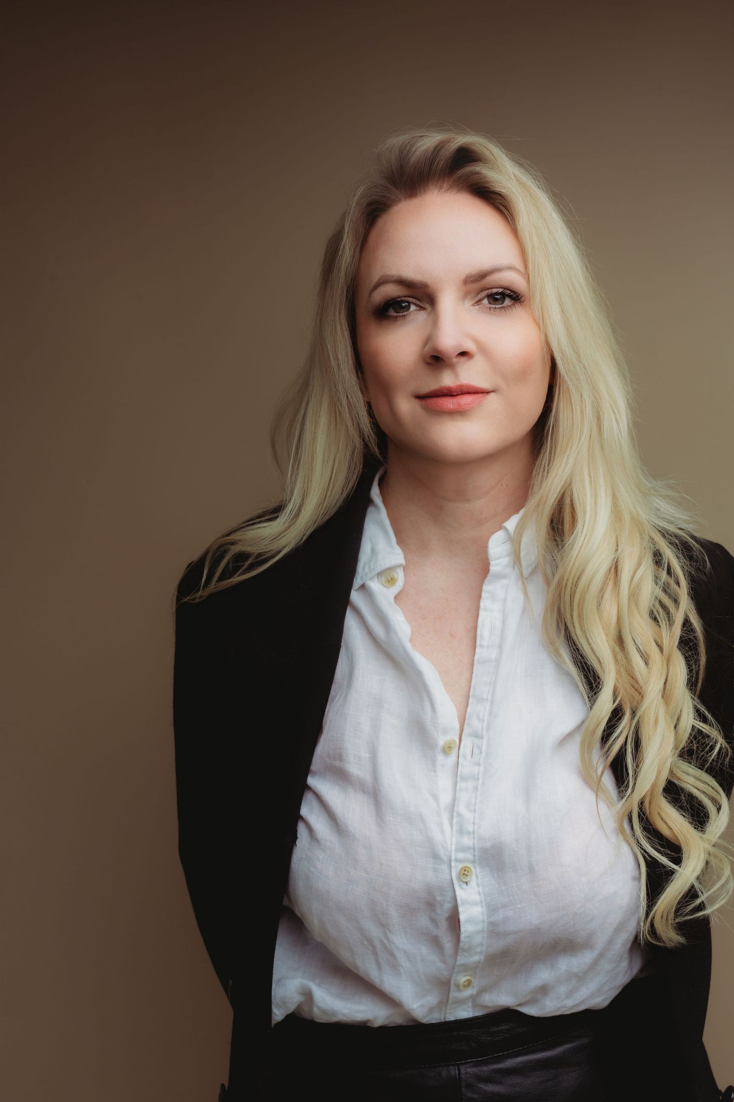Stijlvol zwart blazer en jeans outfit gefotografeerd tegen beige studioachtergrond, portretfotografie Brabant