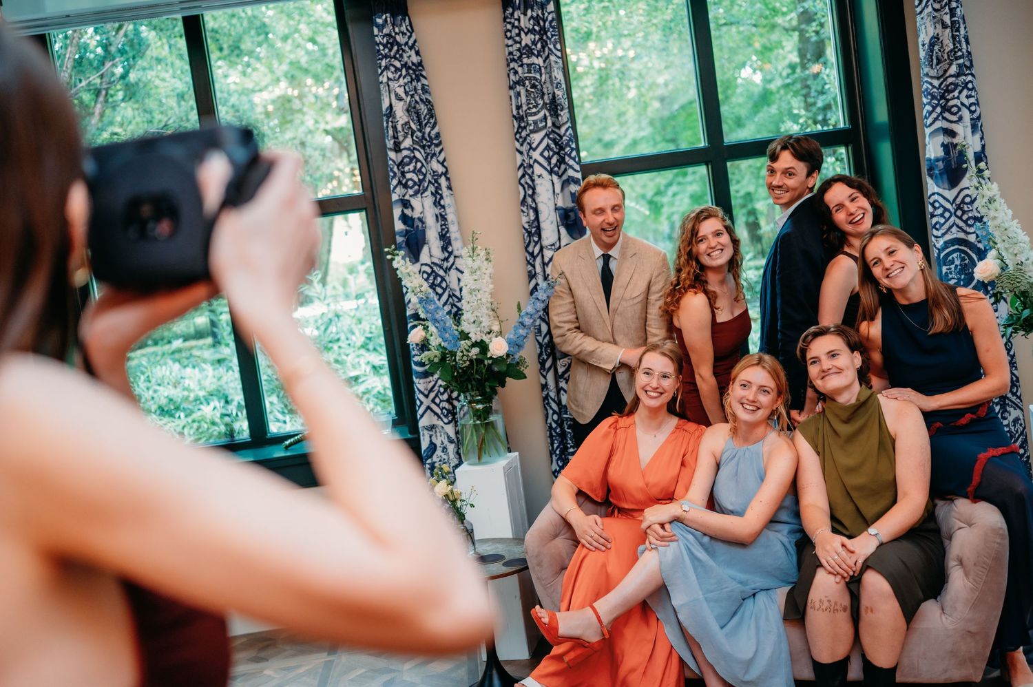 Wedding guests pose for polaroid photo in beautifully decorated blue and white venue.