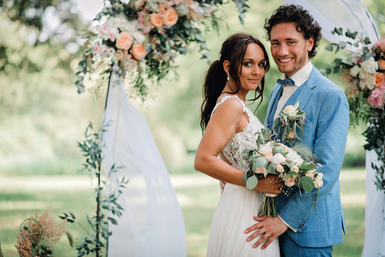 Pasgetrouwden delen intieme momenten in tuin met bloemen en zachte belichting, bruidsfotografie Brabant