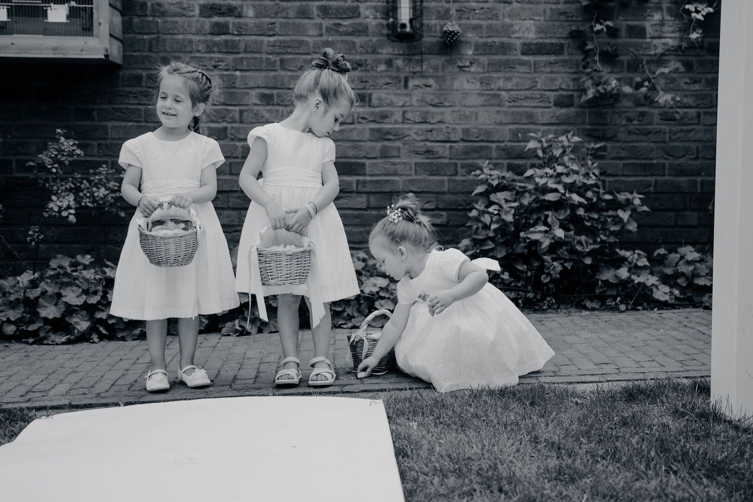 Vintage zwart-wit foto van kinderen die op de trappen van een bakstenen gebouw zitten.