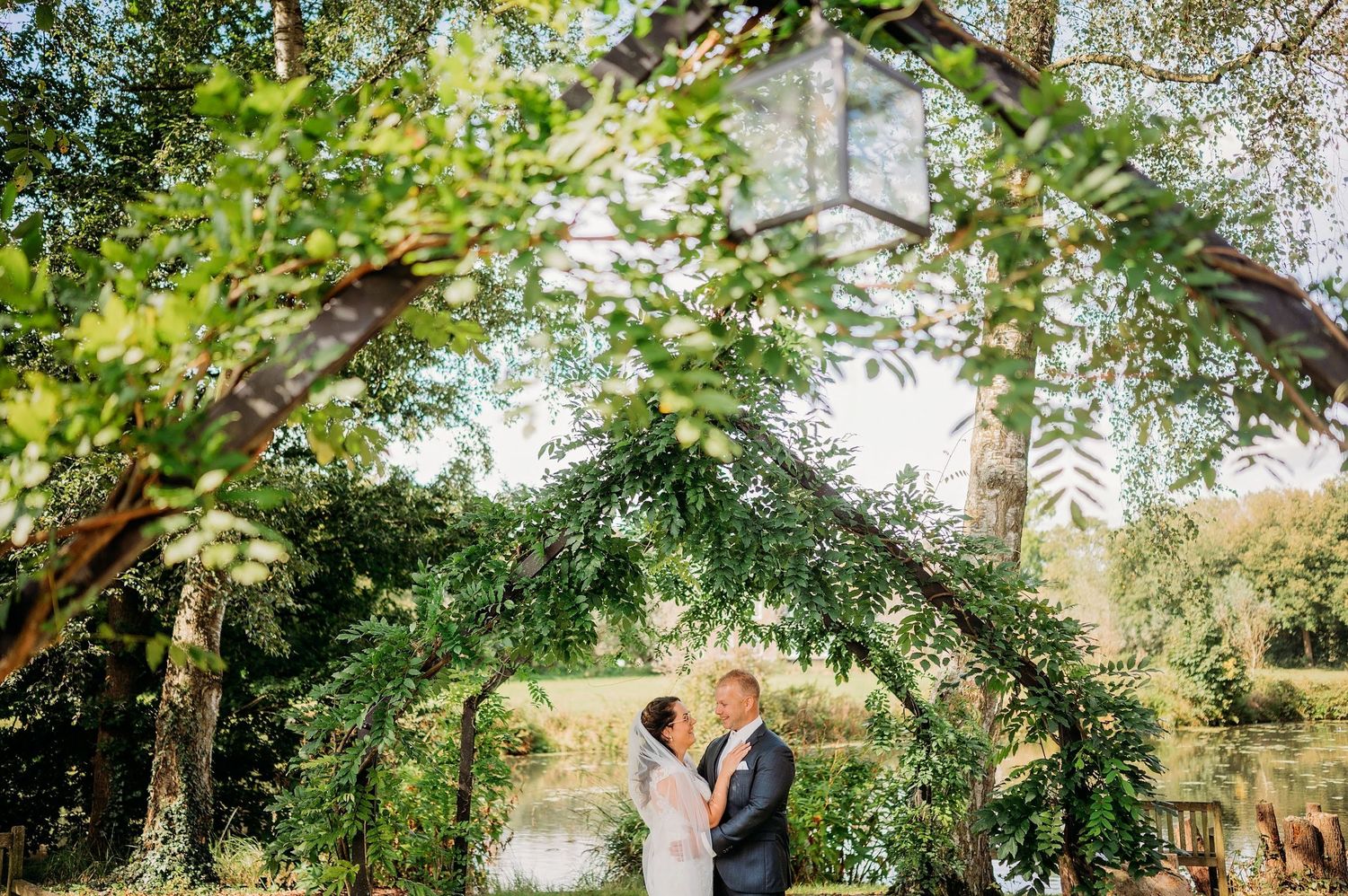 Buitenceremonie met natuurlijke boomboog, witte stoelen en bloemdecoraties, trouwfotografie Brabant.