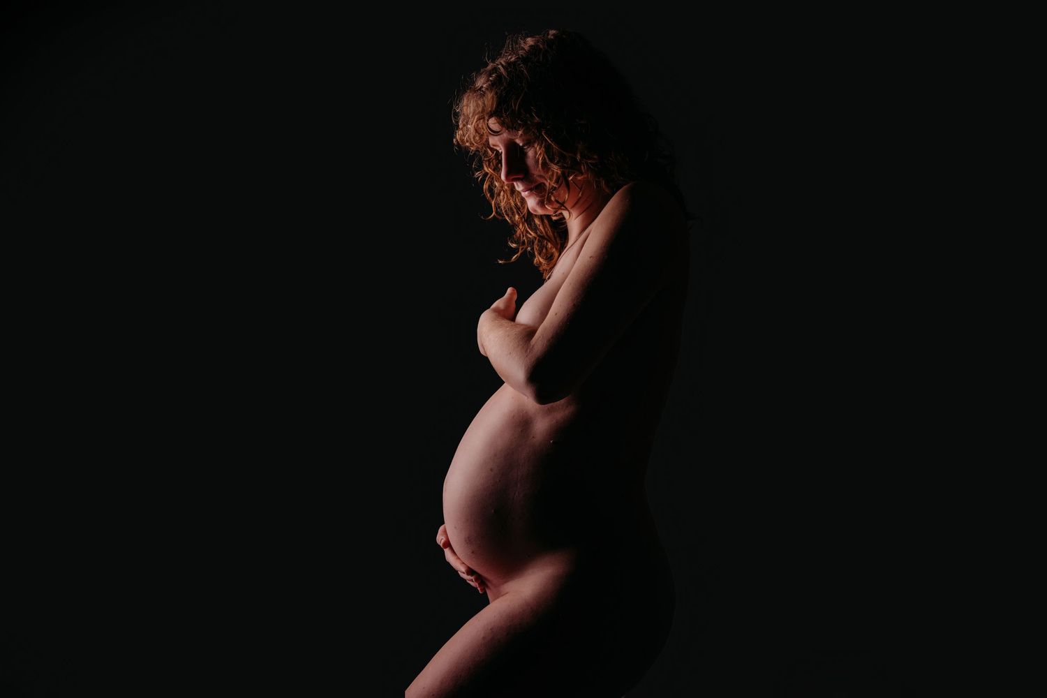 Dramatische zwart-wit silhouet van zwangere vrouw in profiel, zwangerschapsfotografie Brabant