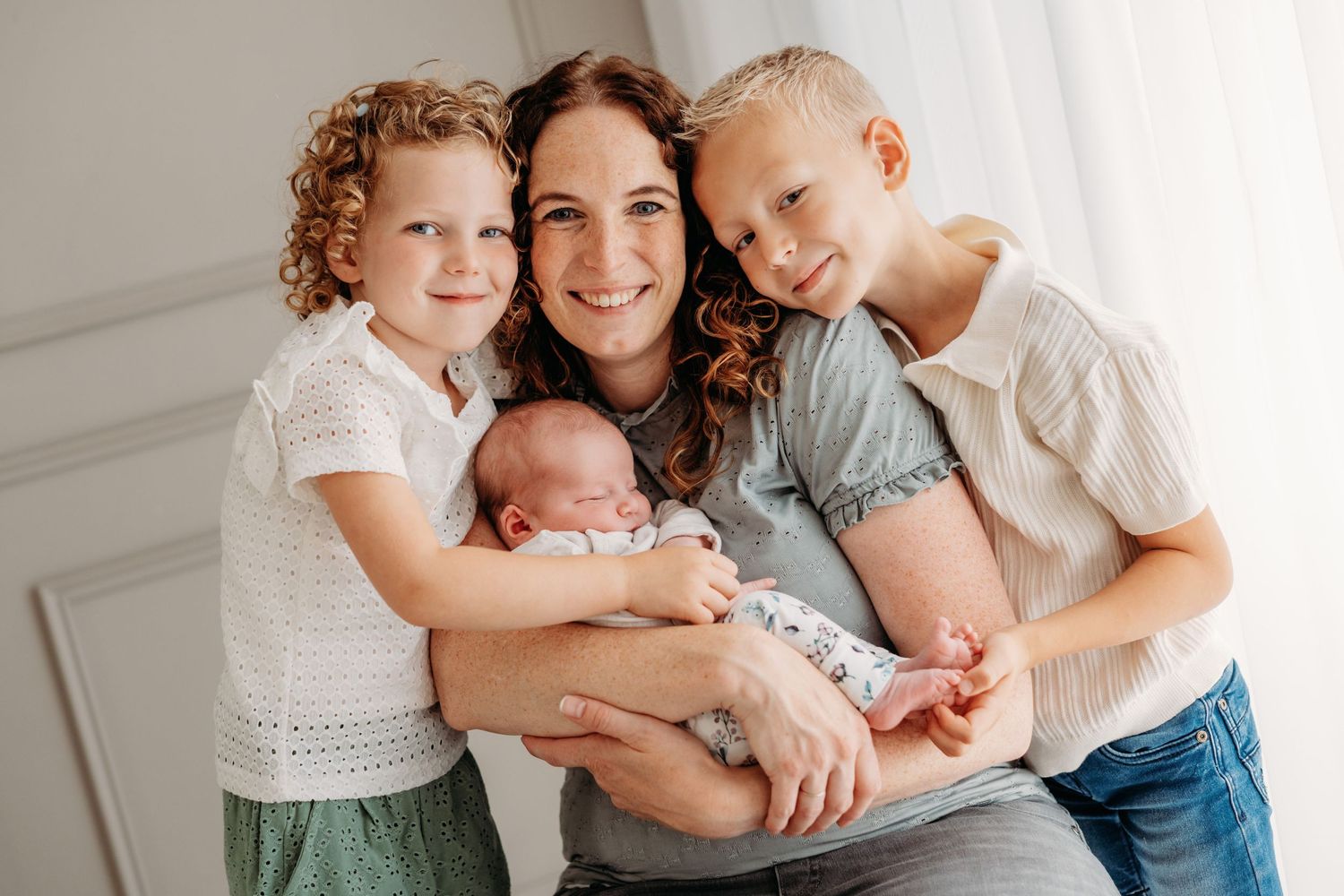 Gelukkige familiefoto met broers en zussen rond pasgeborene, familieshoot Brabant