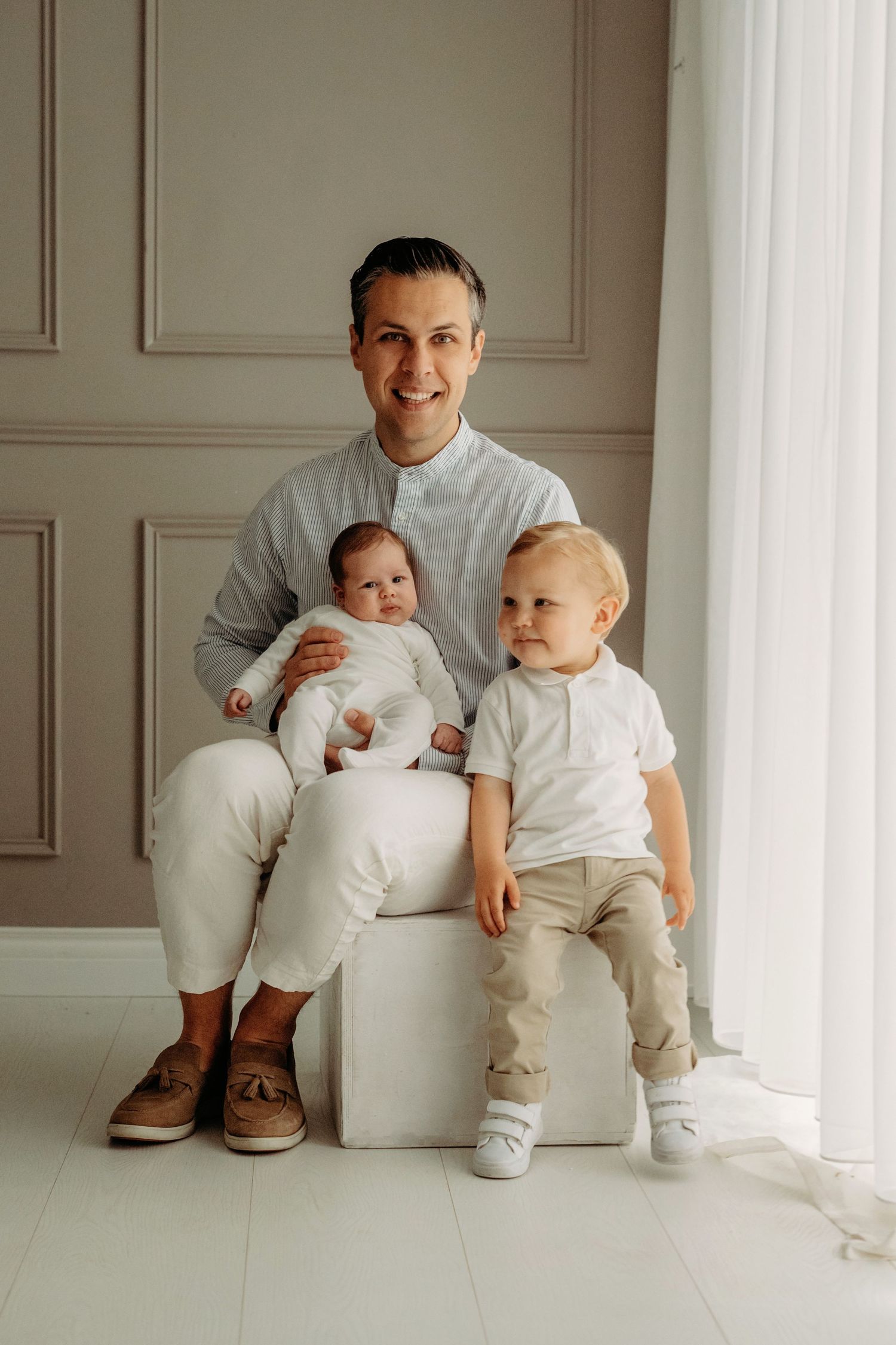 Familiefotoshoot met coördinerende wit- en grijstinten tegen neutrale studioachtergrond, familieshoot Brabant