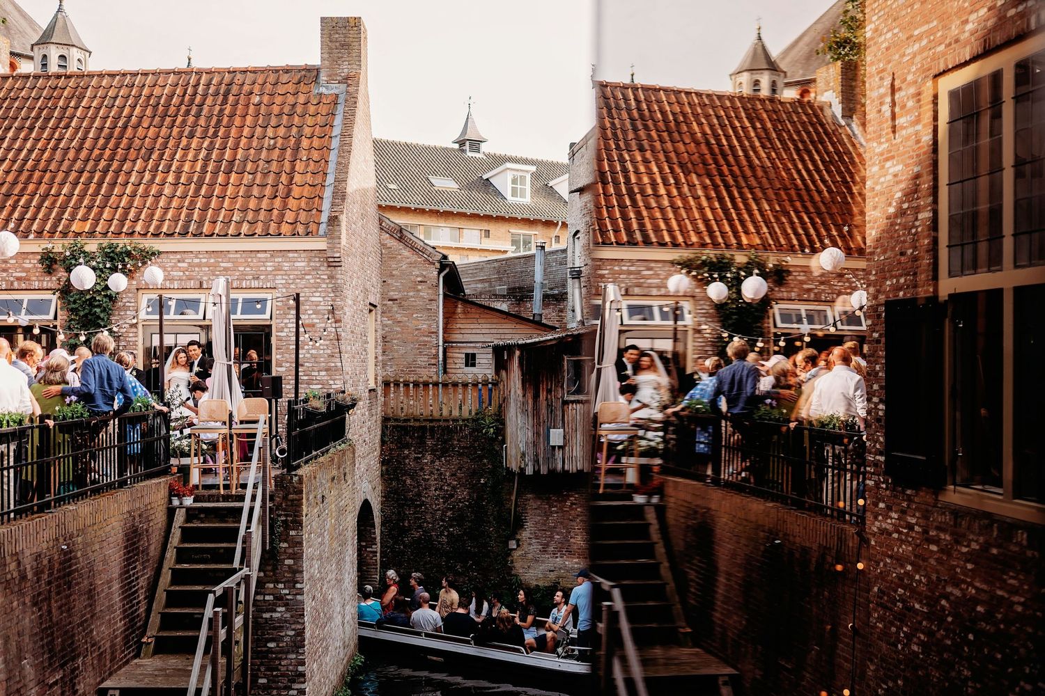 Rooftop trouwreceptie met sfeerverlichting en bakstenen gebouwen in stedelijke omgeving, bruidsfotografie Brabant