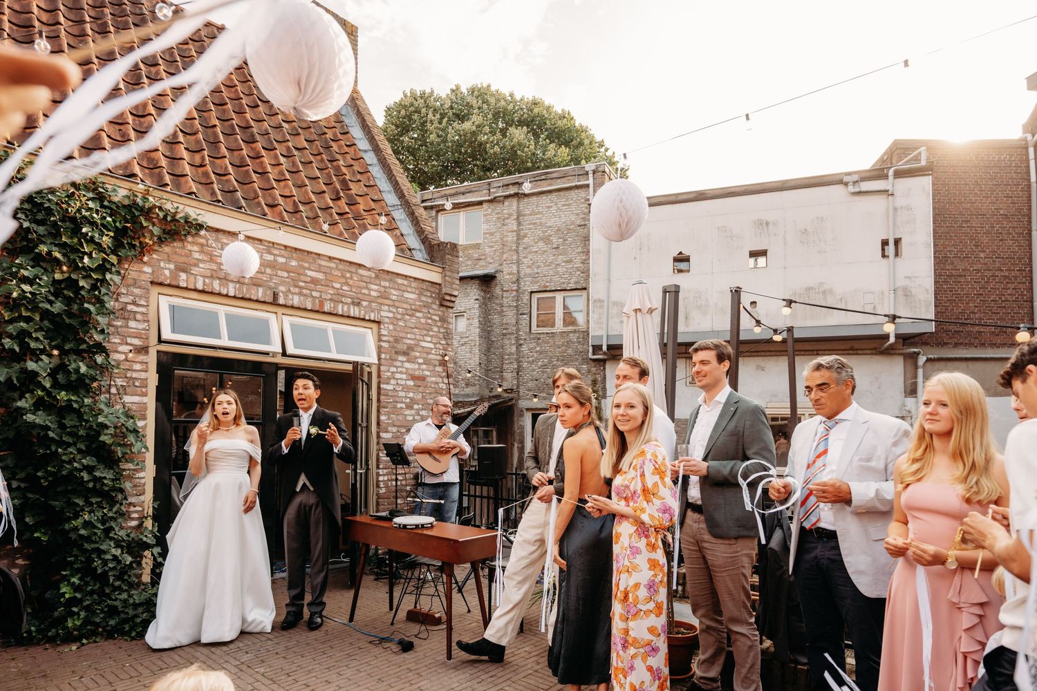 Buitenceremonie in charmante binnenplaats met lichtslingers en bakstenen, bruidsfotografie Noordbrabants Museum Den Bosch, Brabant.