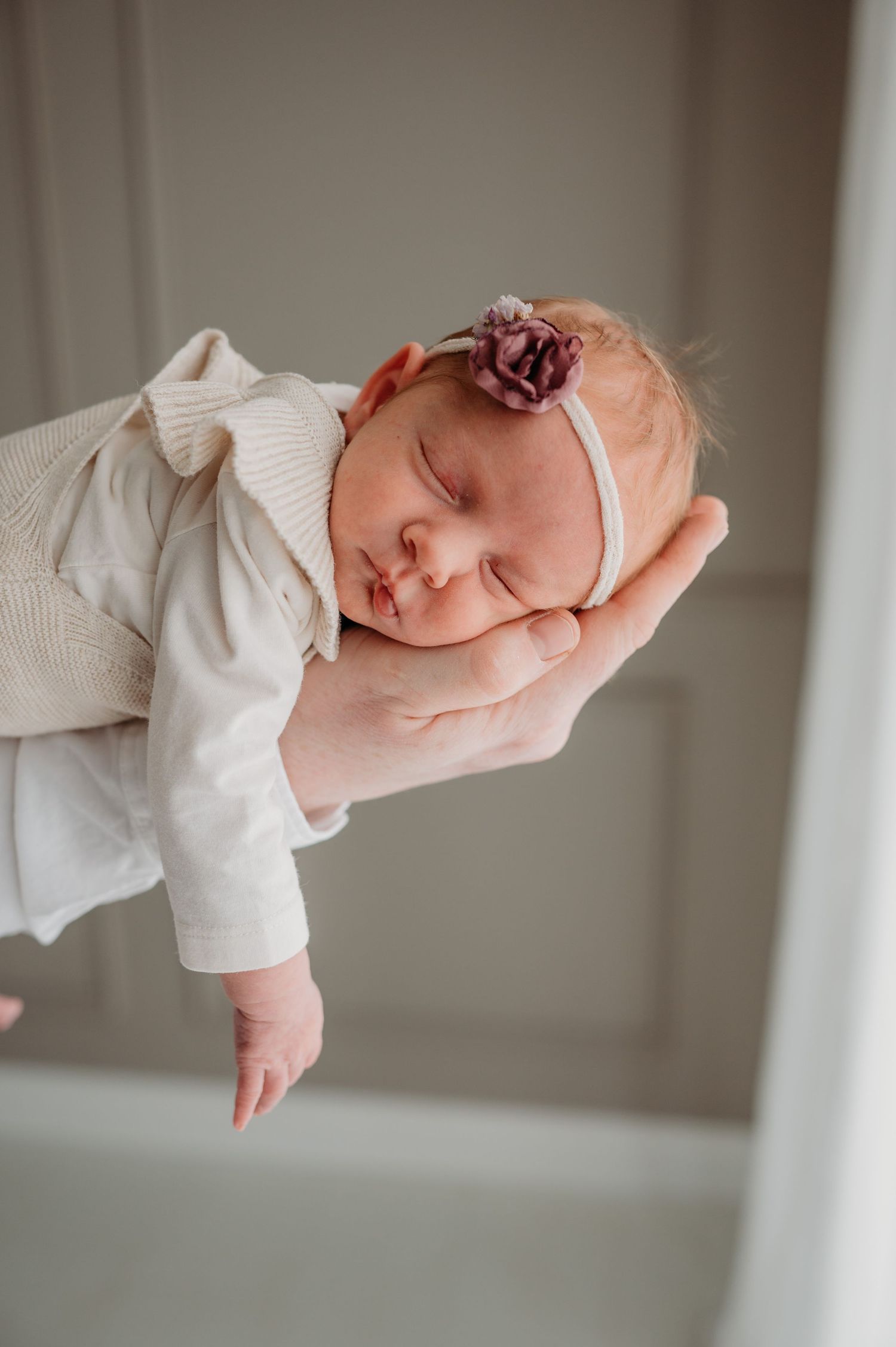 Close-up artistieke foto van pasgeborene in wit tegen neutrale achtergrond, newbornfotografie Brabant