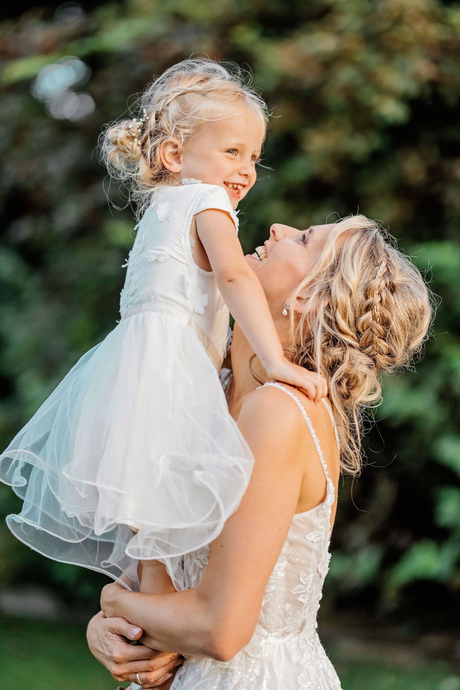 Teder moment tussen bruid en jong kind in witte jurk tijdens outdoor fotoshoot, bruidsfotografie Den Bosch, Noord-Brabant.