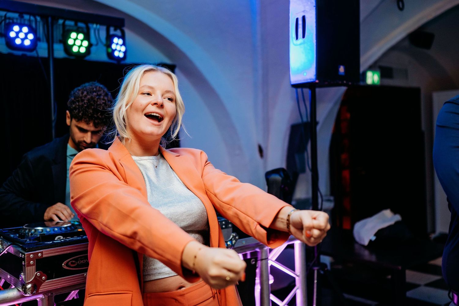 Gast danst uitbundig tijdens trouwfeest met blauw licht, spontane bruidsfotografie en feestreportage in Den Bosch en Brabant.