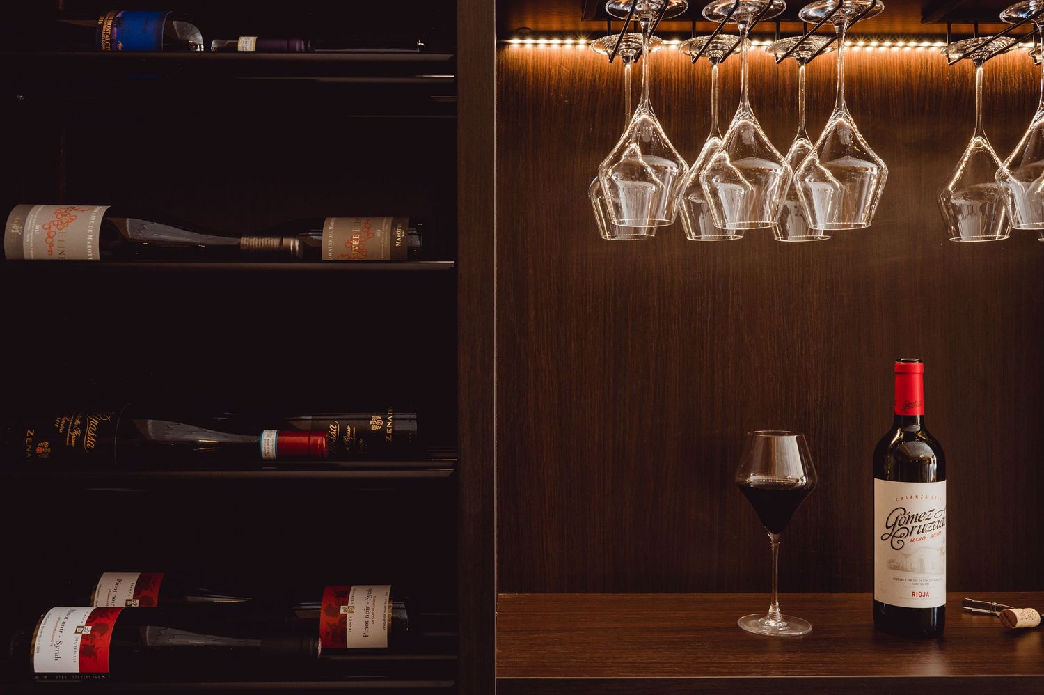 Wijnflessen en glaswerk op houten planken in een stijlvolle bar met warm licht, gefotografeerd voor hospitality fotografie in regio Den Bosc