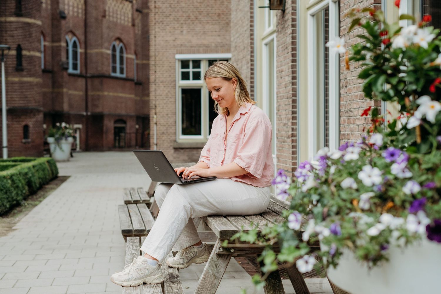 Mensen werken op laptops buiten bij historisch bakstenen gebouw, zakelijke fotografie Brabant